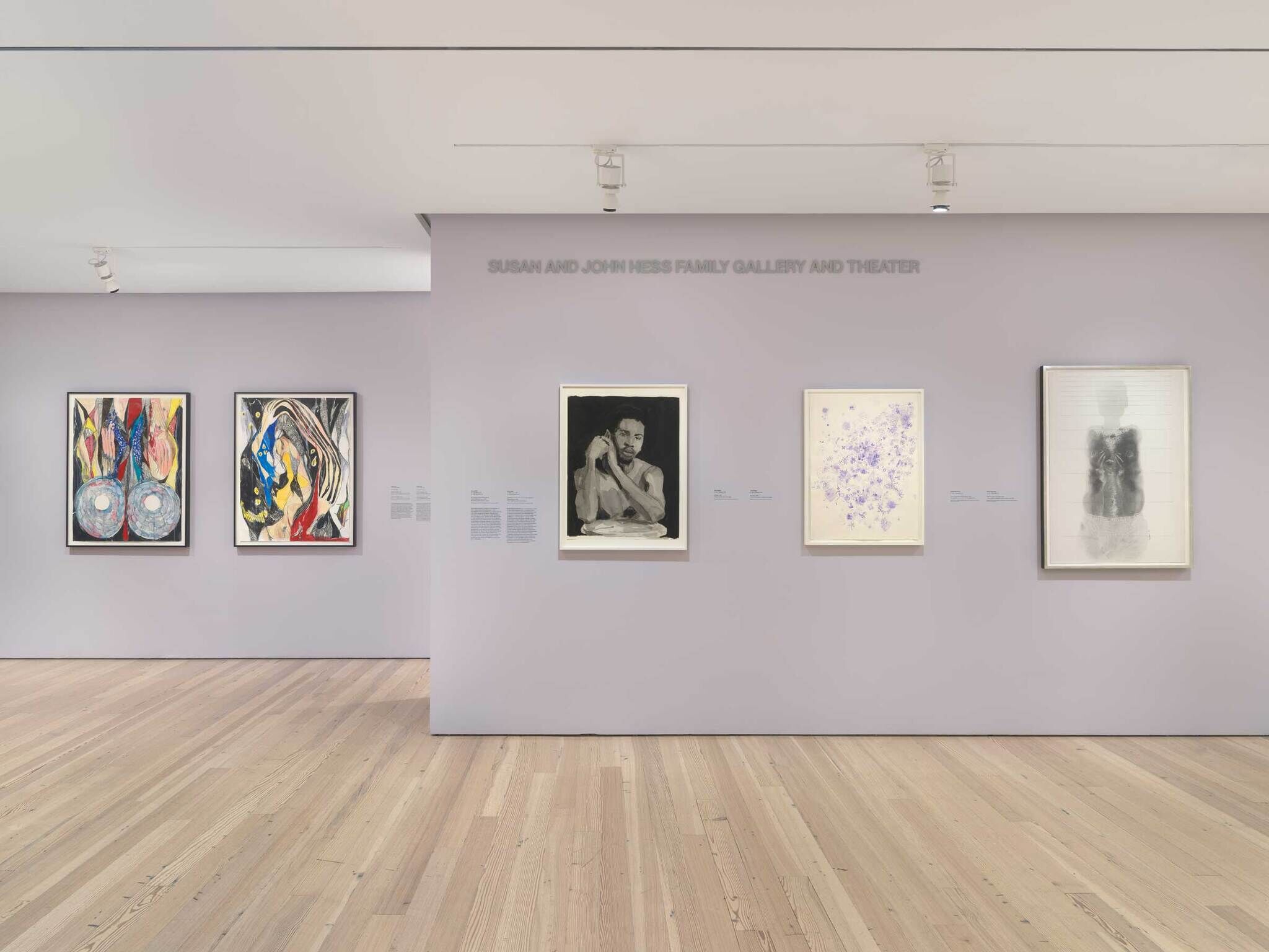 Art gallery with five framed artworks on light purple walls, featuring abstract and figurative pieces. Wooden floor and overhead lighting.