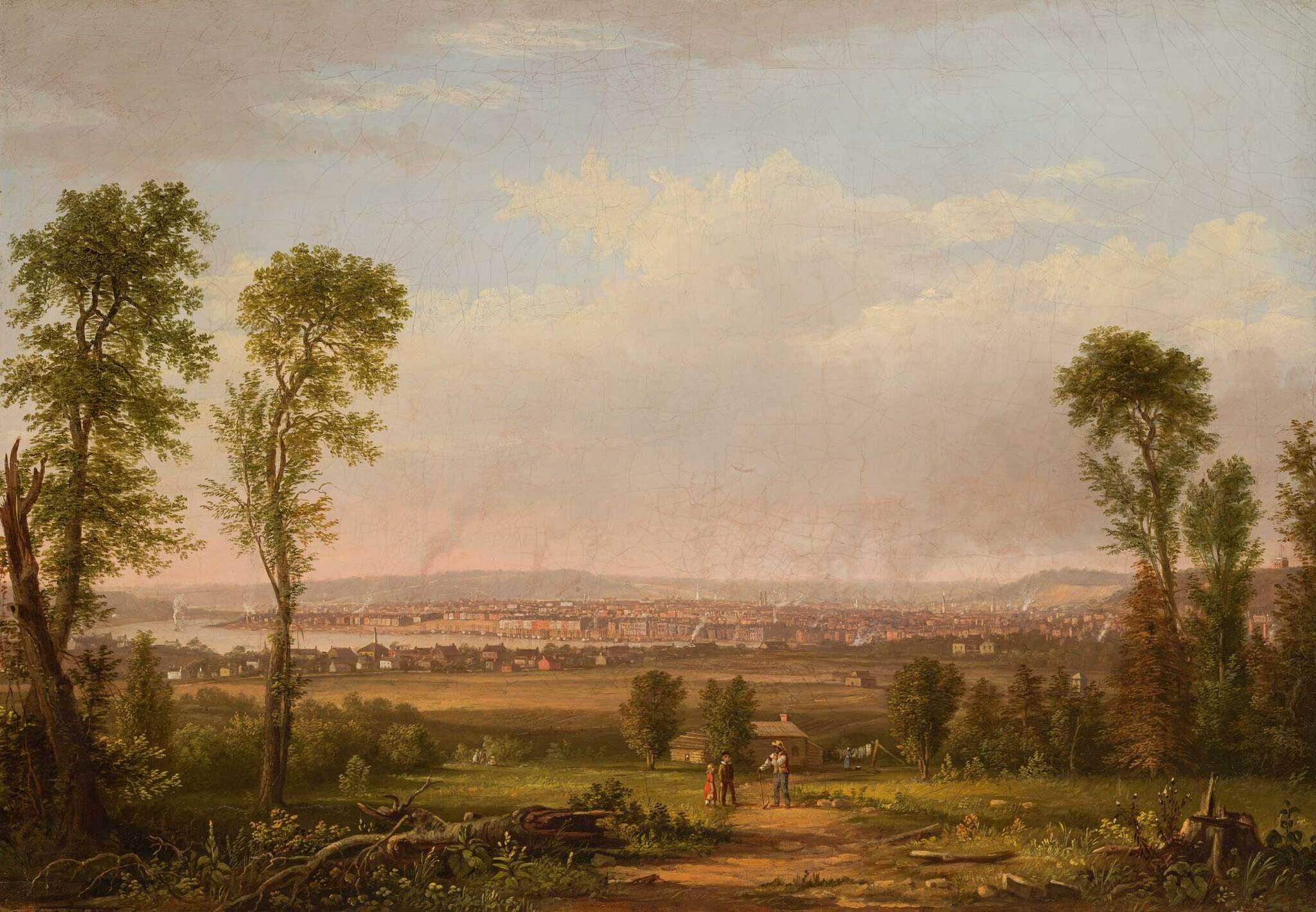 A pastoral scene with people in the foreground, trees on either side, and a distant view of a town under a partly cloudy sky.