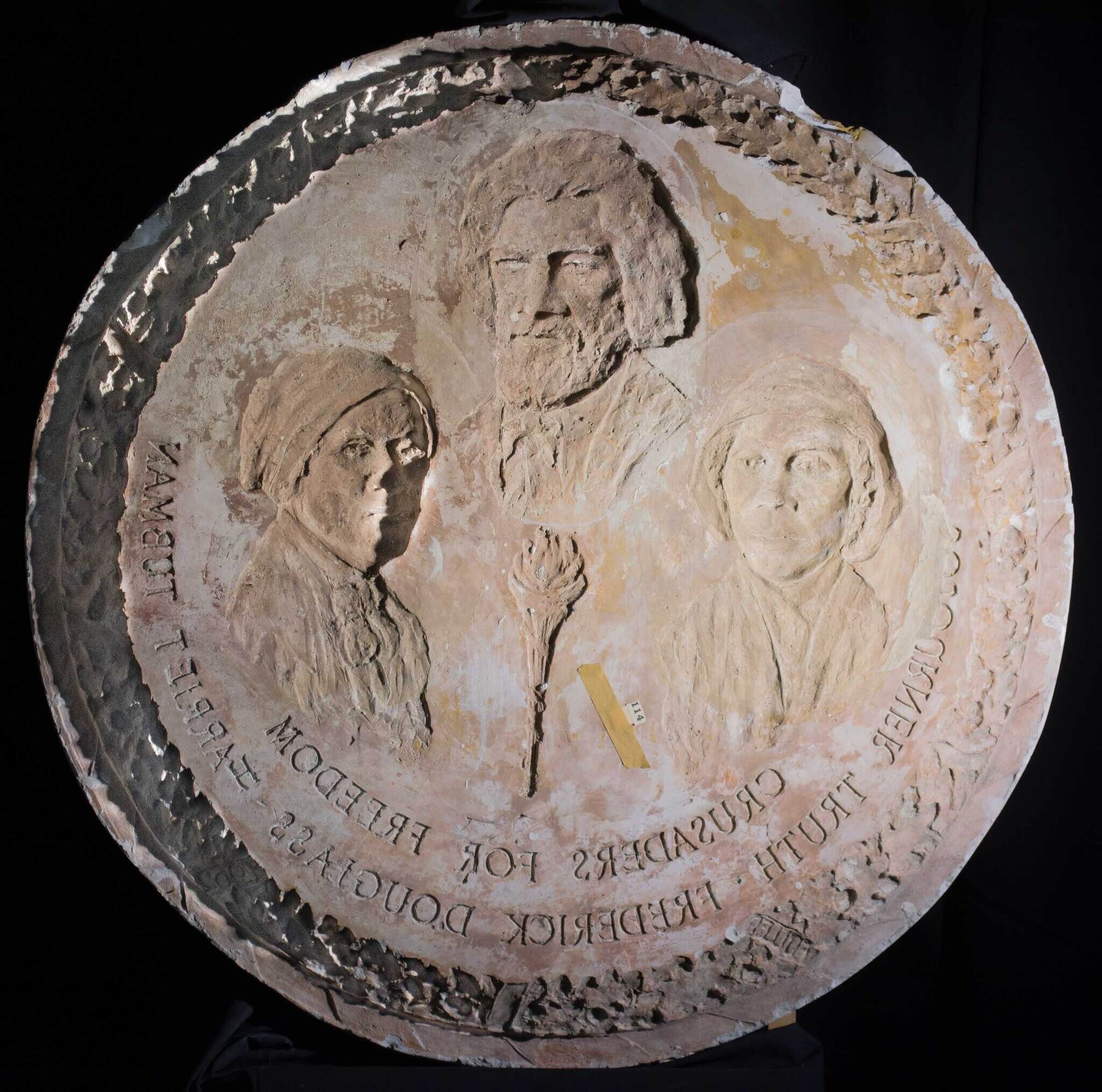 Circular stone relief featuring three figures and the text "Guardians for Freedom: Harriet Tubman, Frederick Douglass, Sojourner Truth."