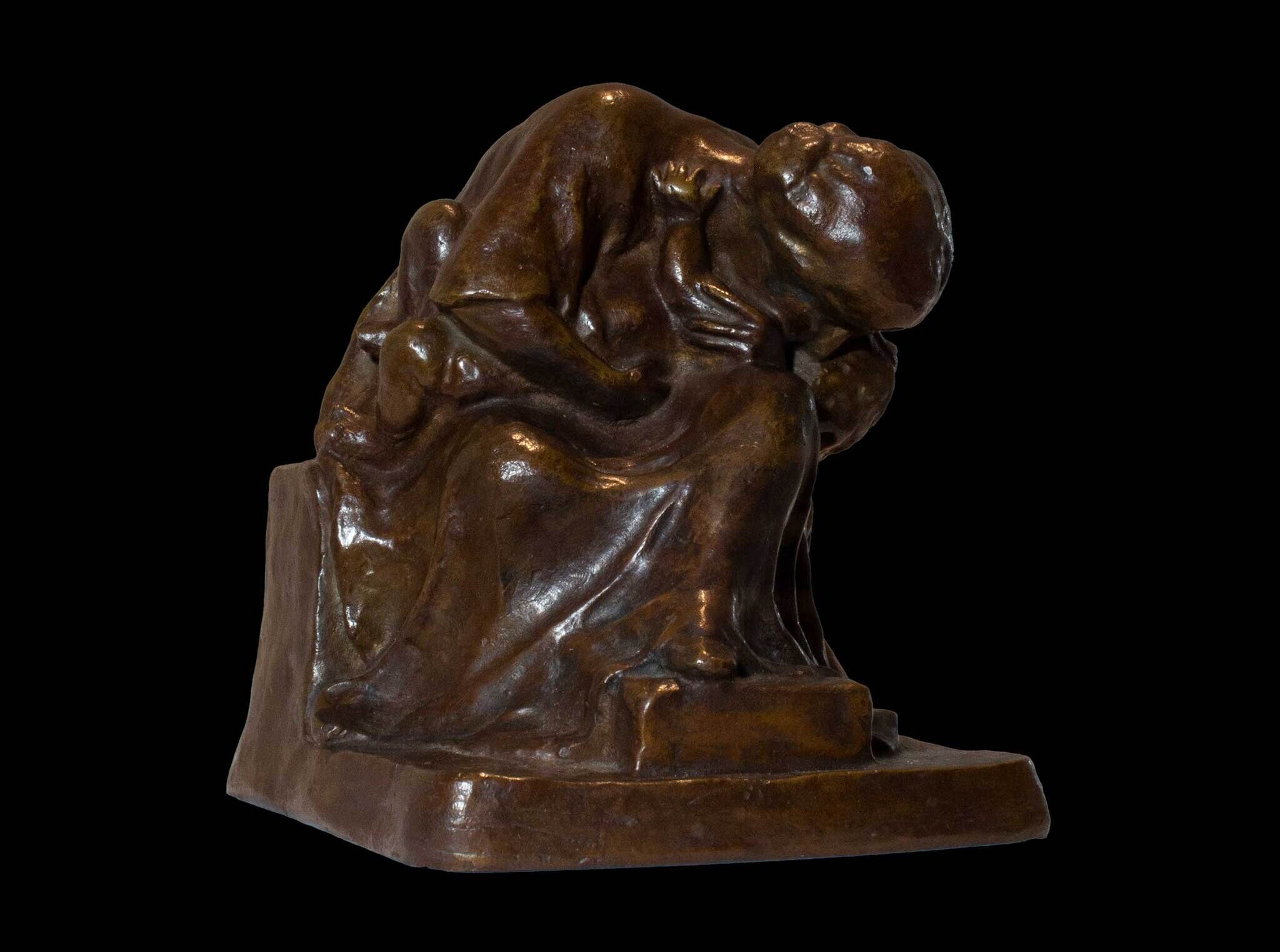 Bronze sculpture of a seated, cloaked figure with head bowed and hands clasped, conveying a sense of contemplation or sorrow.