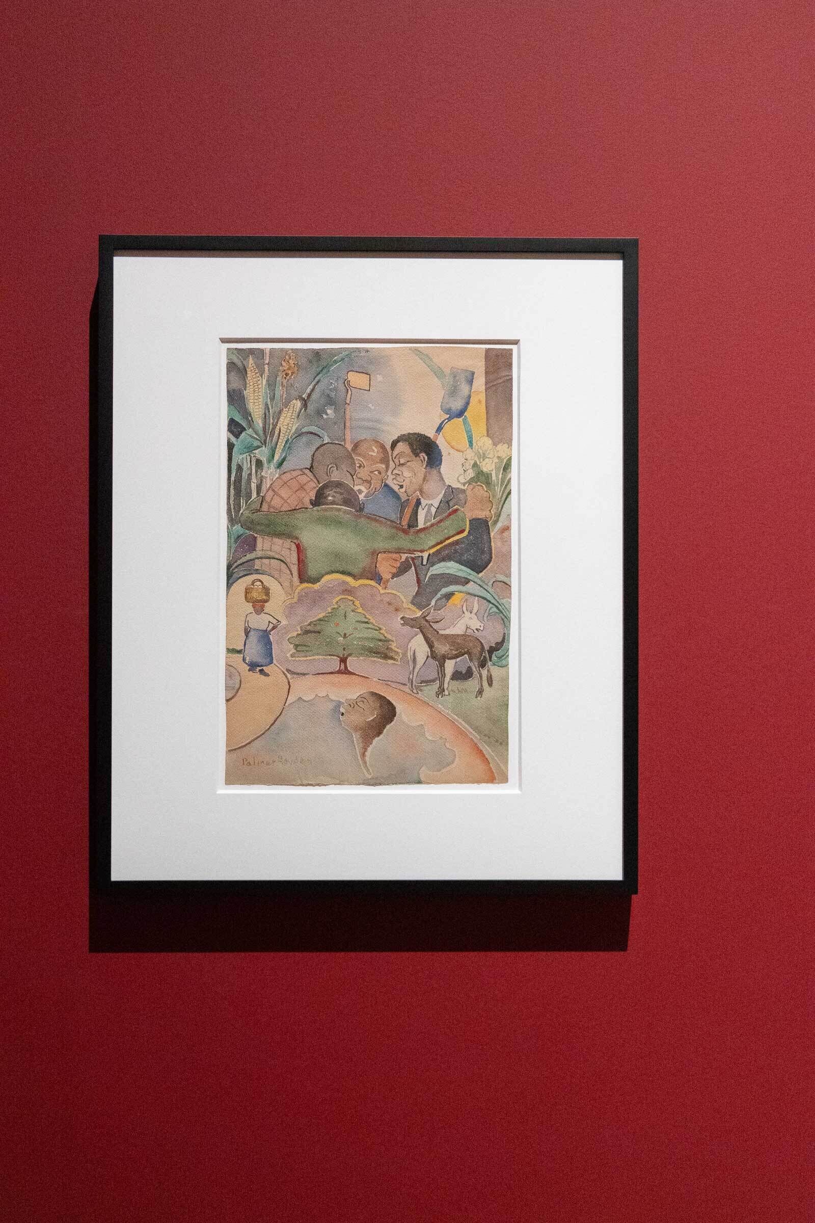 Framed painting on a red wall depicting a group of people embracing, with various symbolic elements like a tree, a goat, and a person in water.