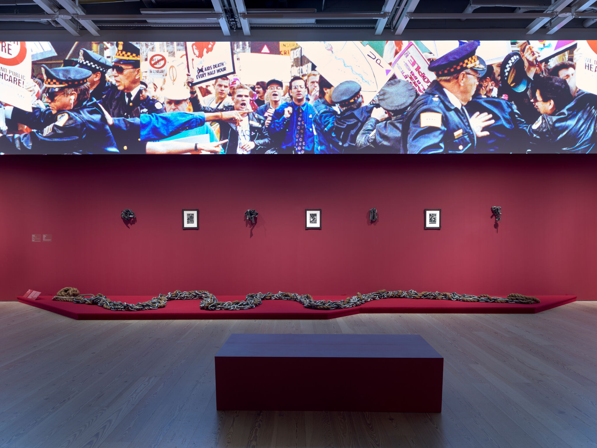 Exhibit with red walls, framed art, and a long chain on display.