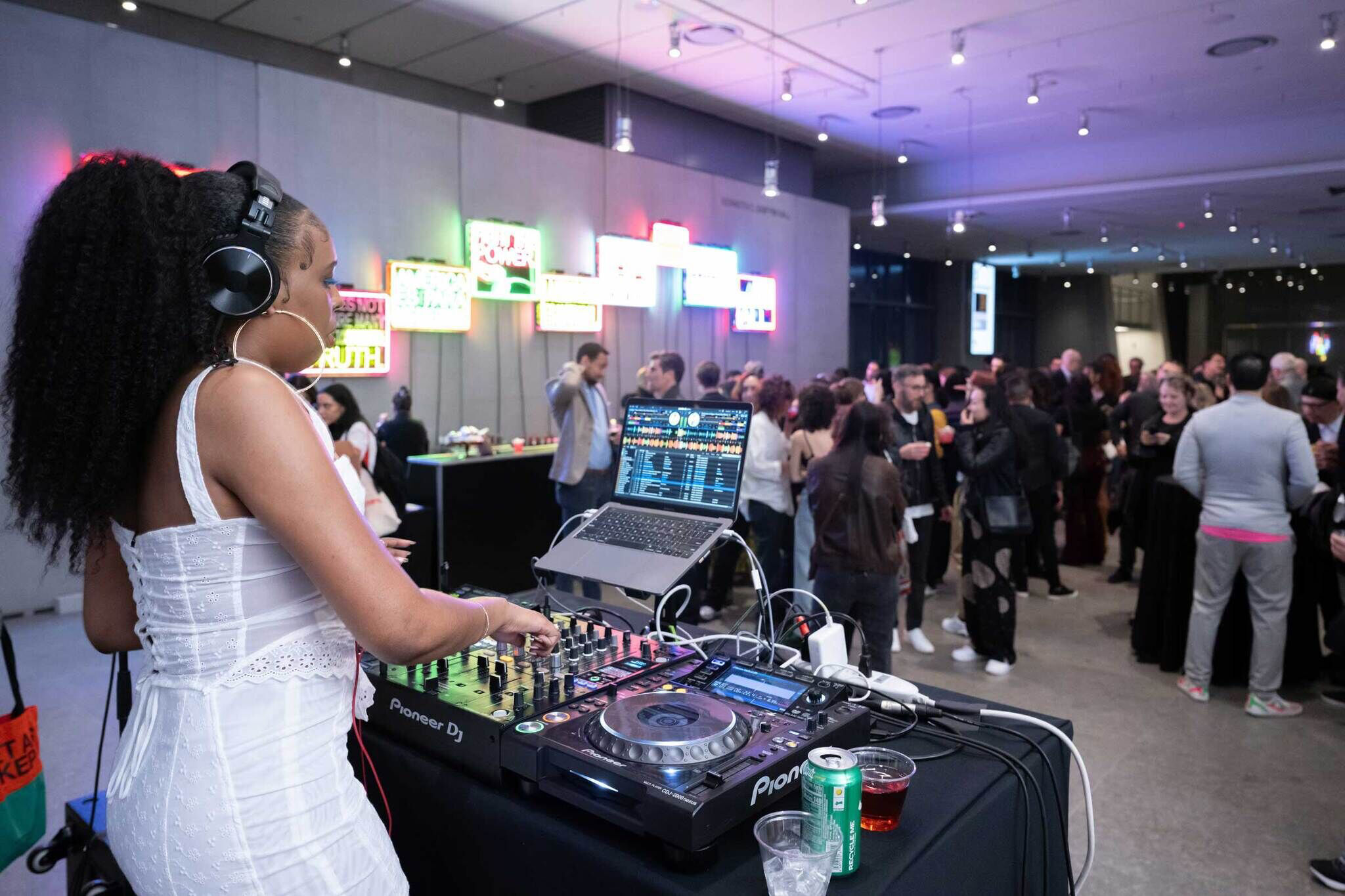 DJ Bembona playing a set in front of a large crowd at the Whitney Museum lobby.