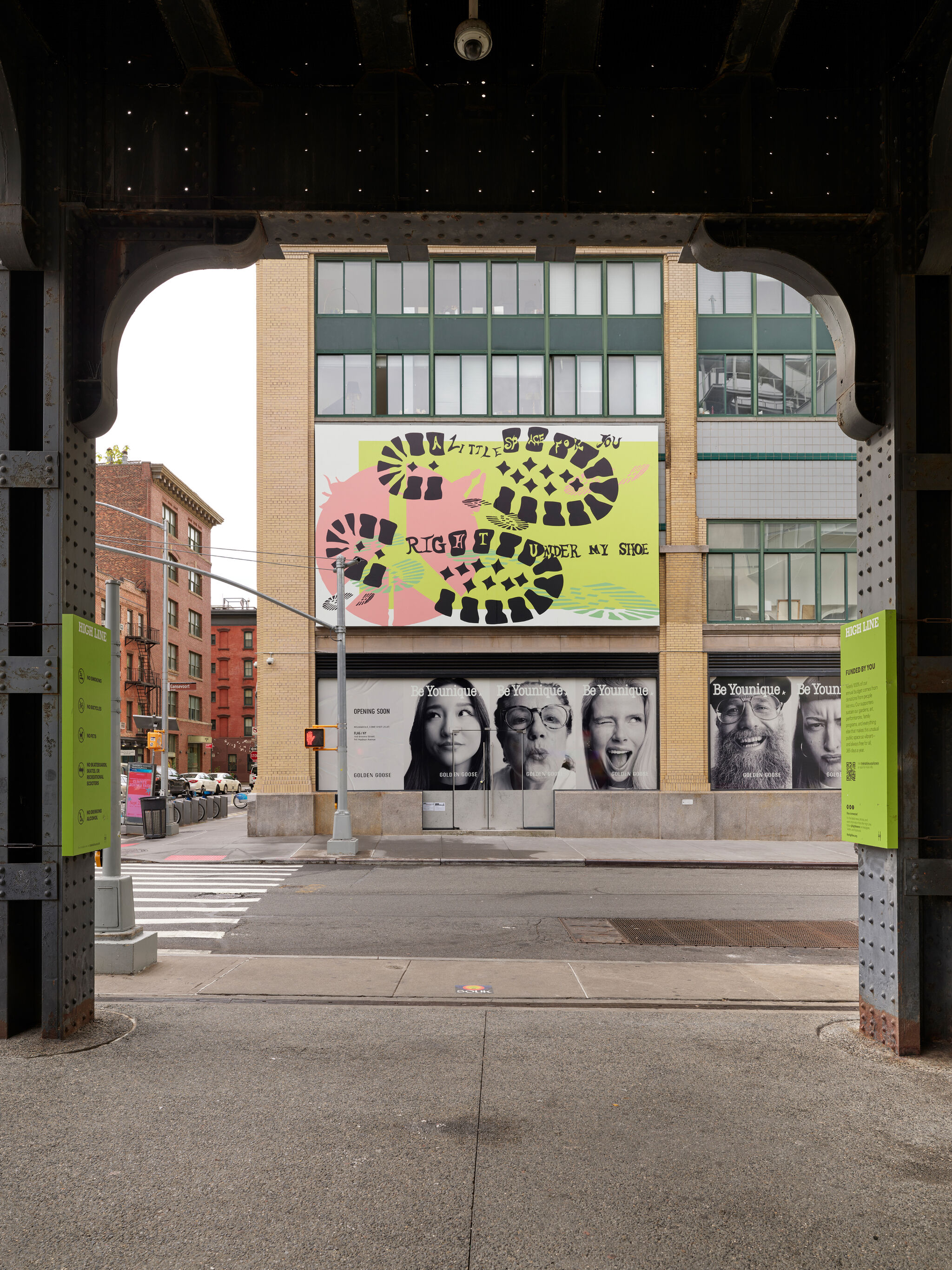 View through an archway of a city street, featuring mural by Raque Ford, with text "A little space for you right under my shoe."