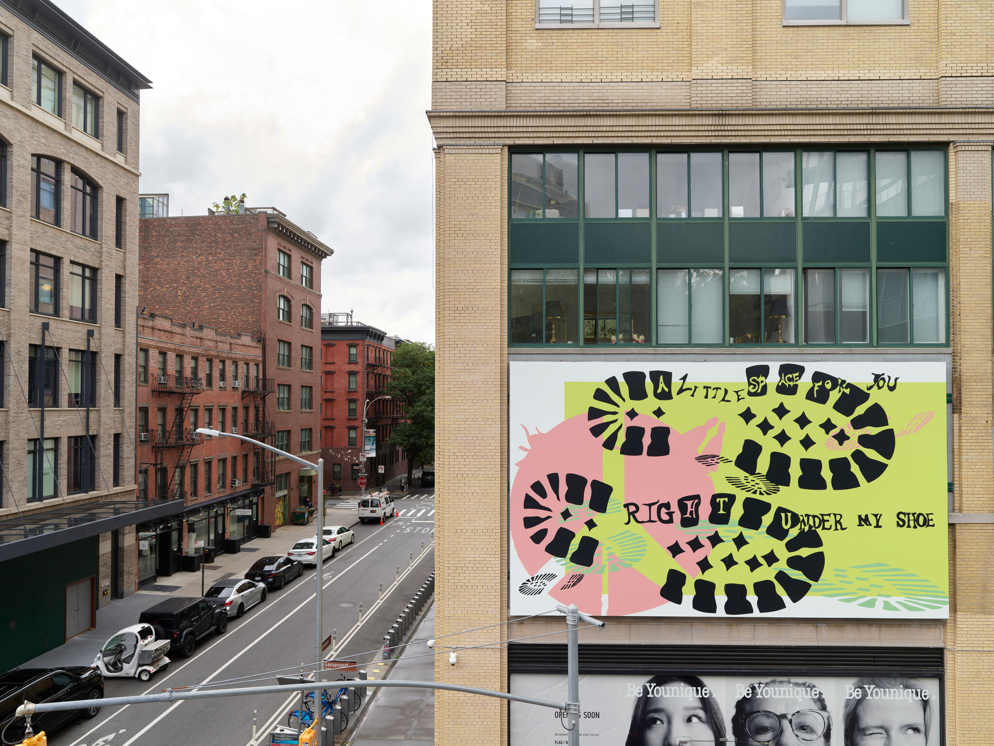 Street view with a colorful mural on a building, featuring abstract shapes and the text "A little space for you right under my shoe."