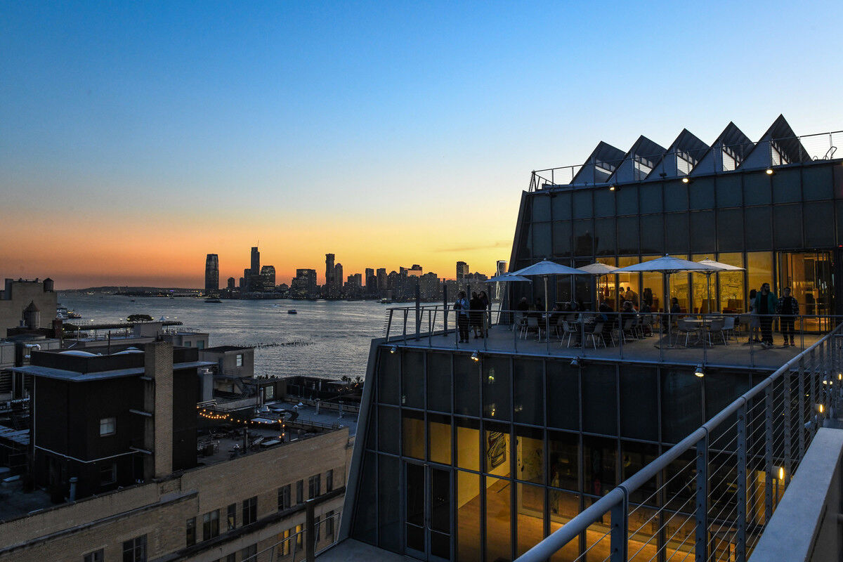 View of the Whitney's terrace during sunset, with ocean and tall buildings in the back.