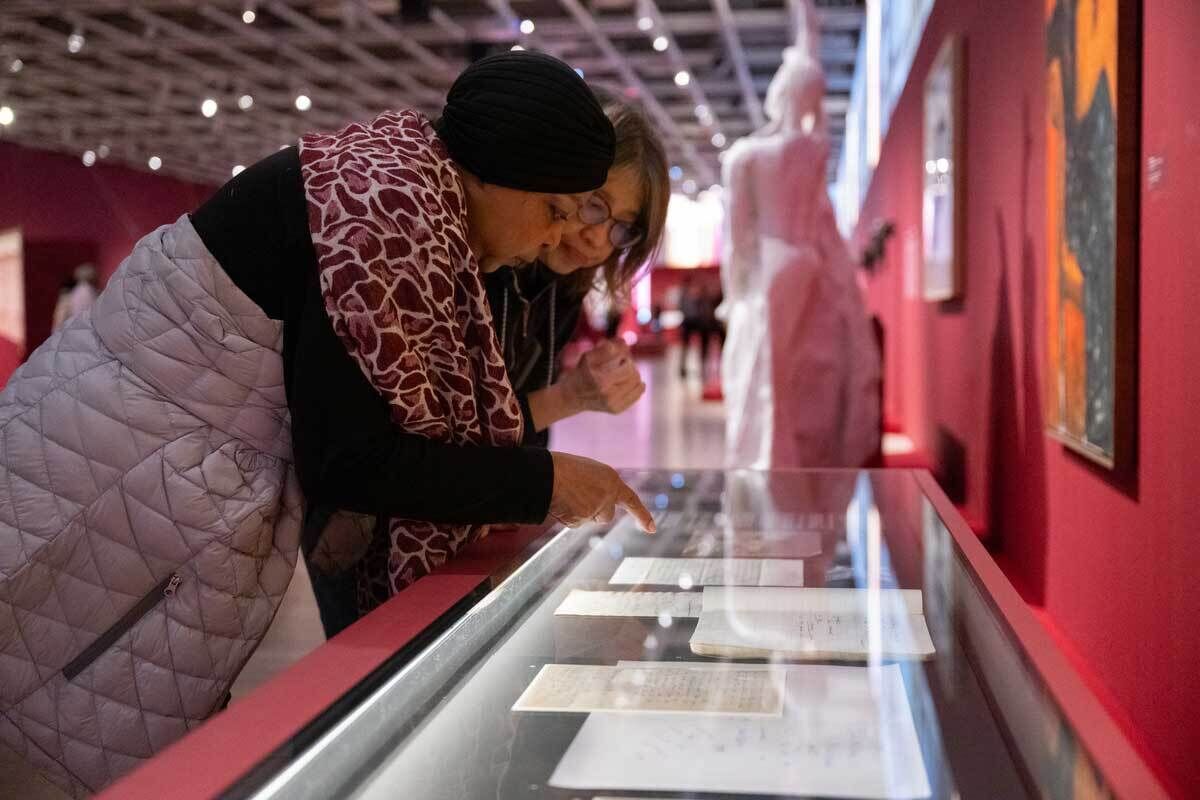 Two women examine archival materials in a museum case.