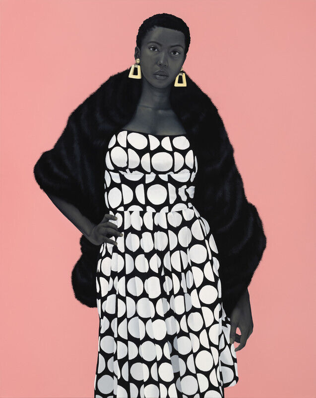 Woman in a black and white polka dot dress with a black fur stole, wearing geometric earrings, against a pink background.