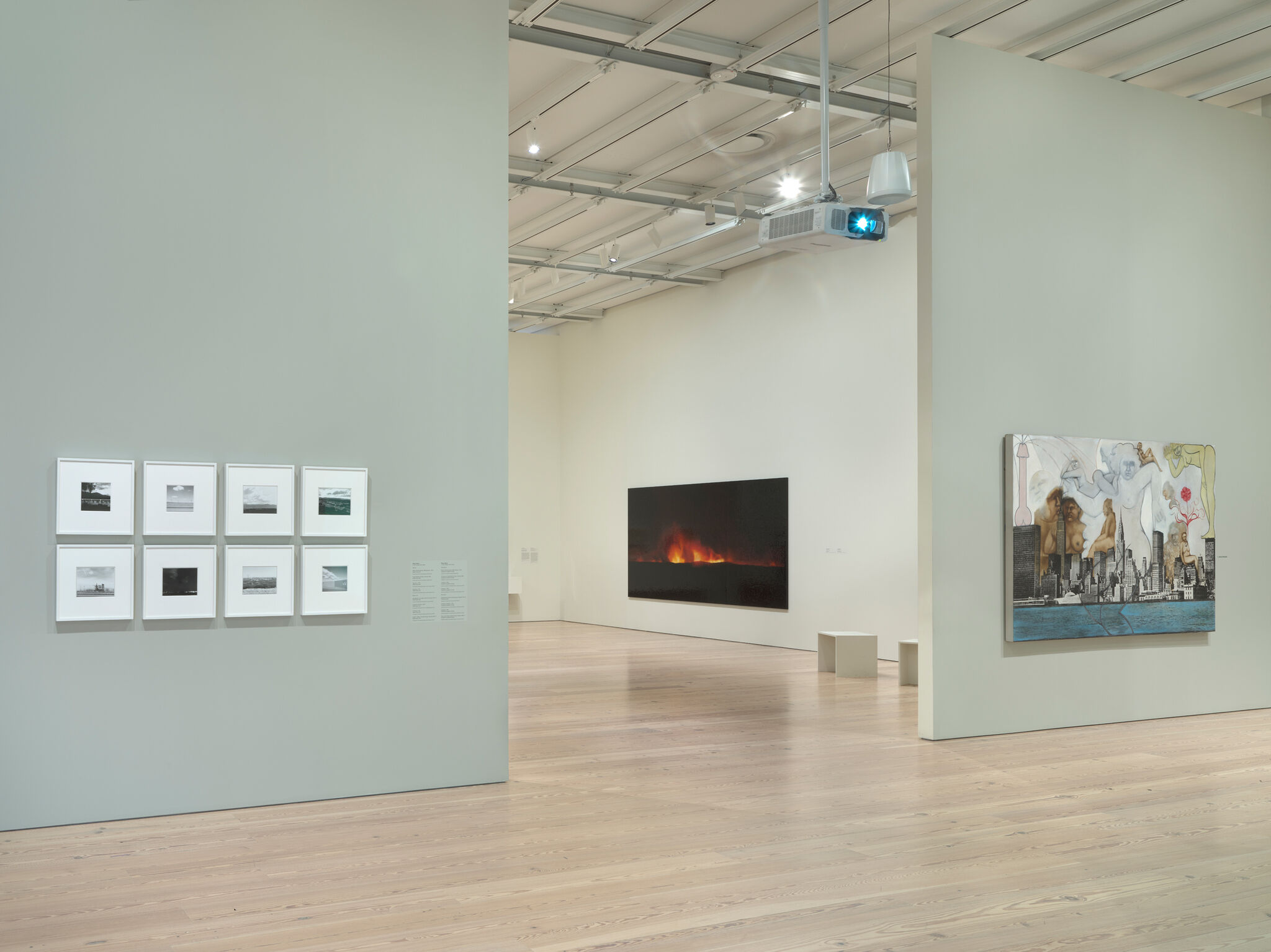 Art gallery with framed photos on the left wall, a large fiery landscape painting in the center, and a colorful cityscape on the right.