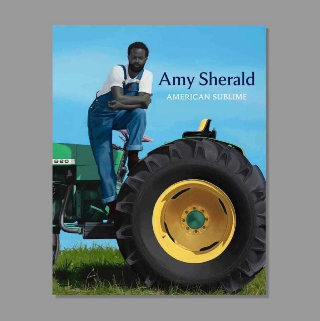 An art catalogue that says Amy Sherald: American Sublime with the painting of an American man on a tractor in jean overalls.