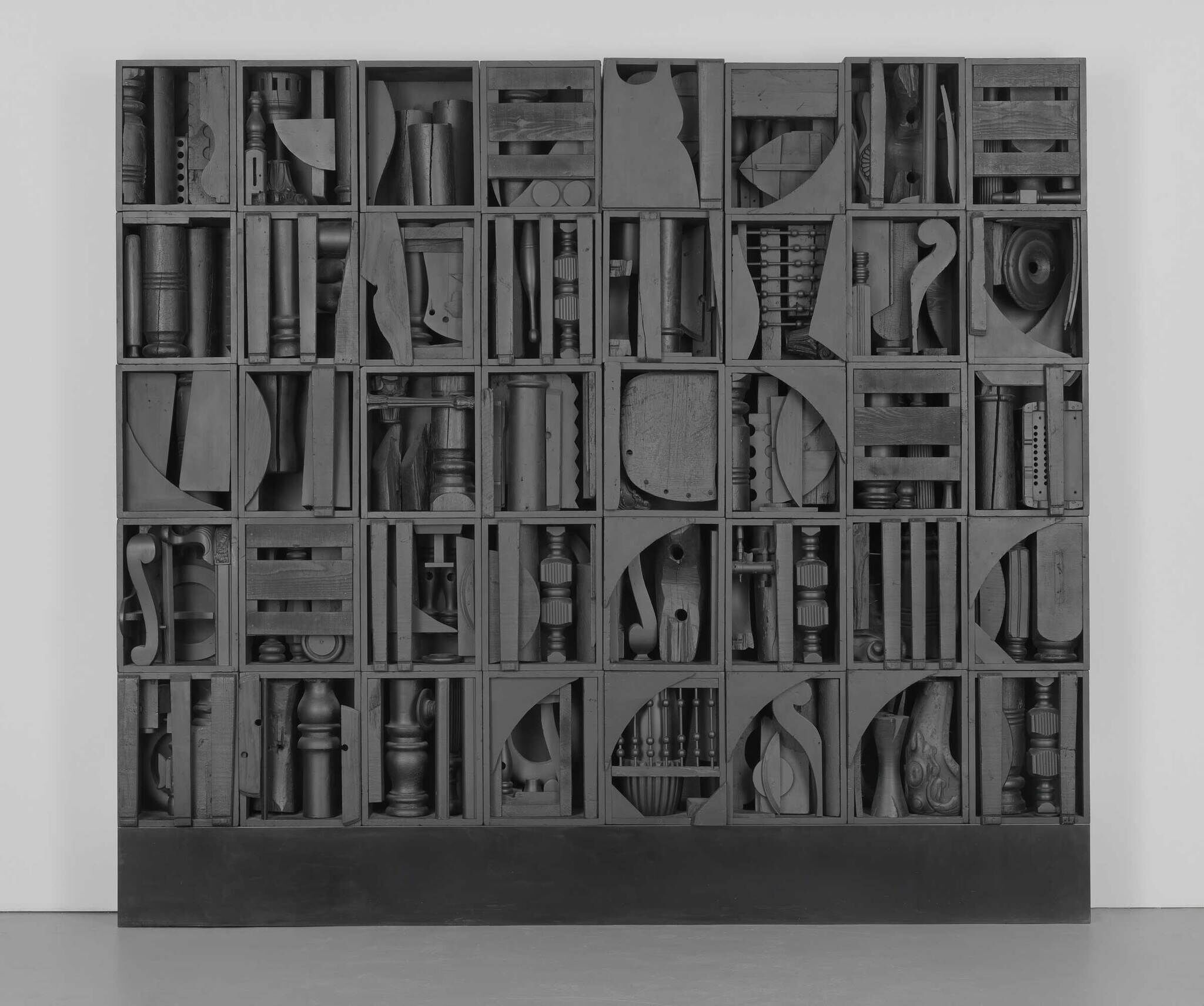 A large wooden wall sculpture made of many small boxes, each filled with different carved and shaped wooden objects.