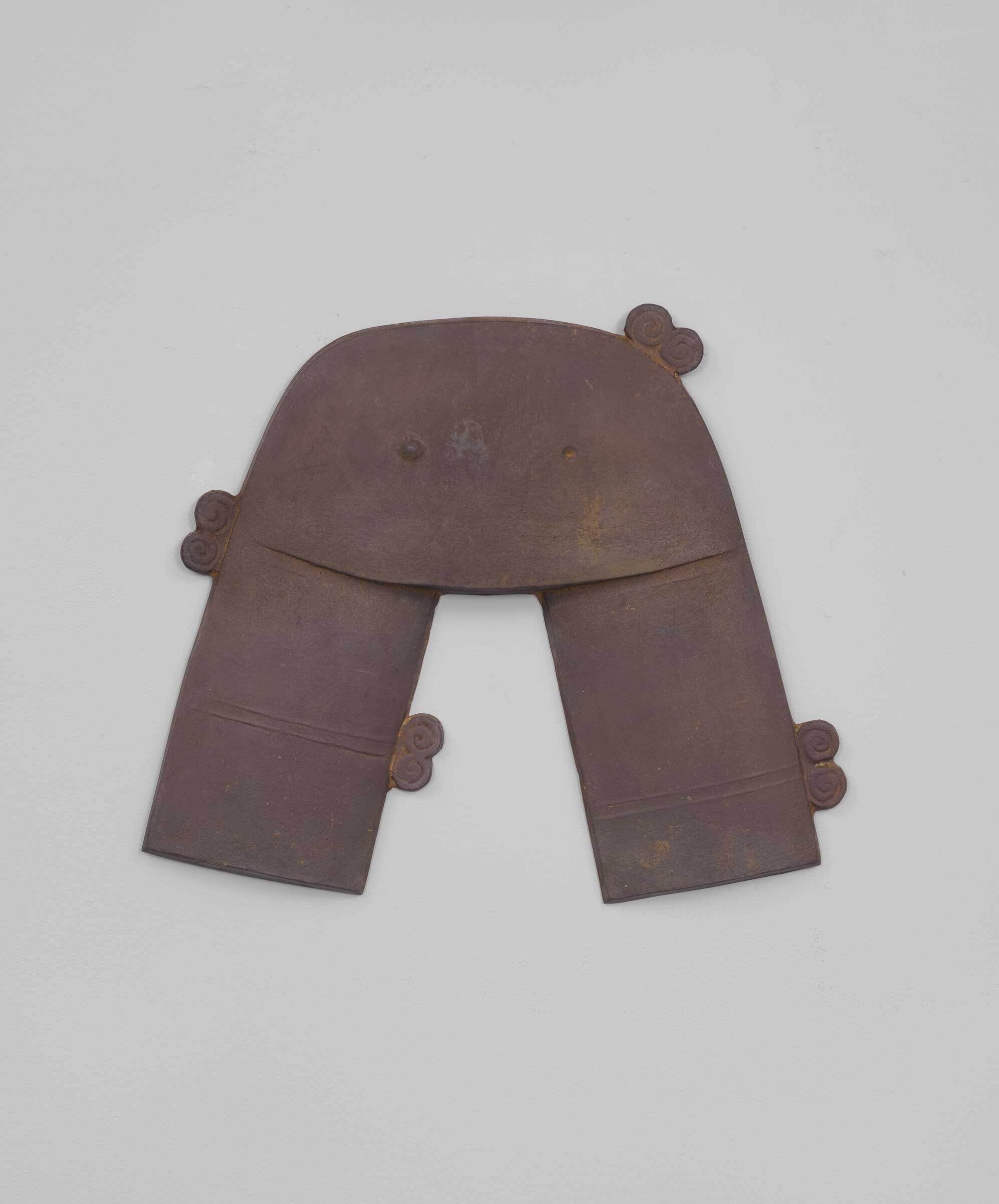 Brown, U-shaped metal object with two legs and four spiral decorations, displayed against a plain white background.