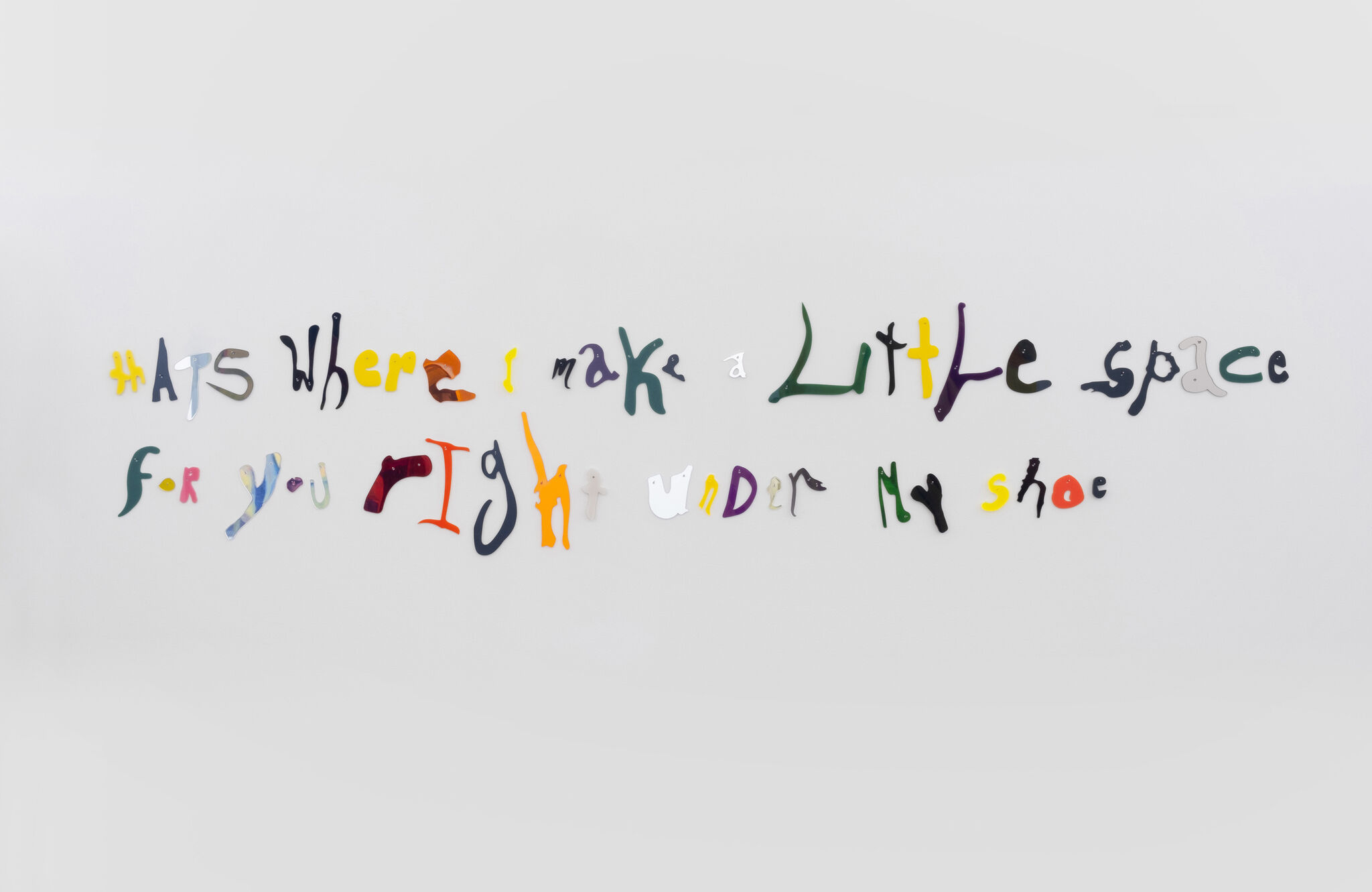 Colorful, irregular letters on a wall spell: “thats where i make a little space for you right under my shoe.”