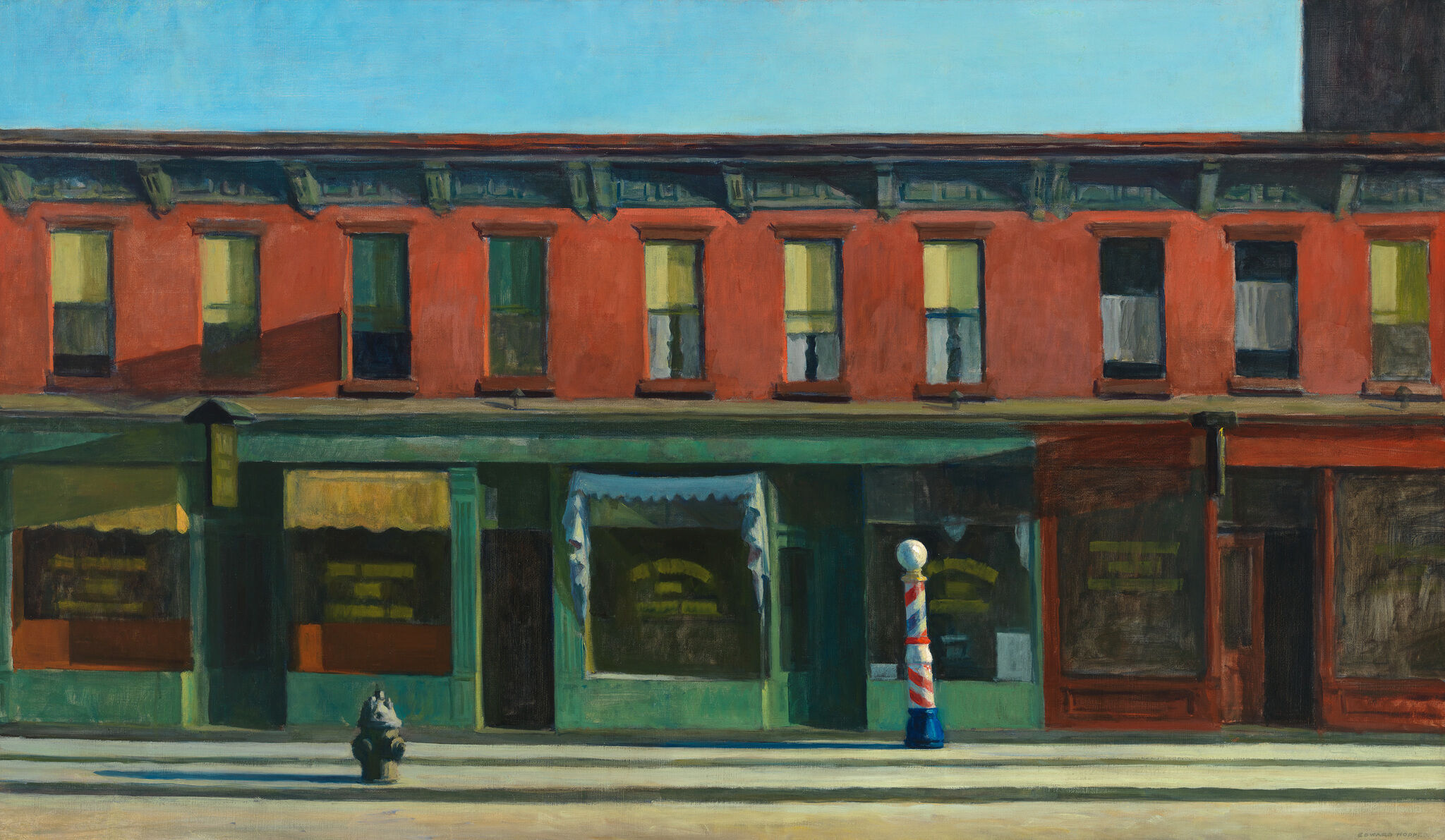 A quiet street with a red brick building, closed windows, and a striped barber pole on the sidewalk.
