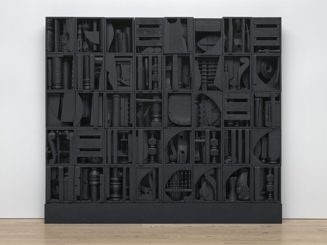 Large black wooden cabinet filled with various carved and shaped objects, all painted the same dark color.