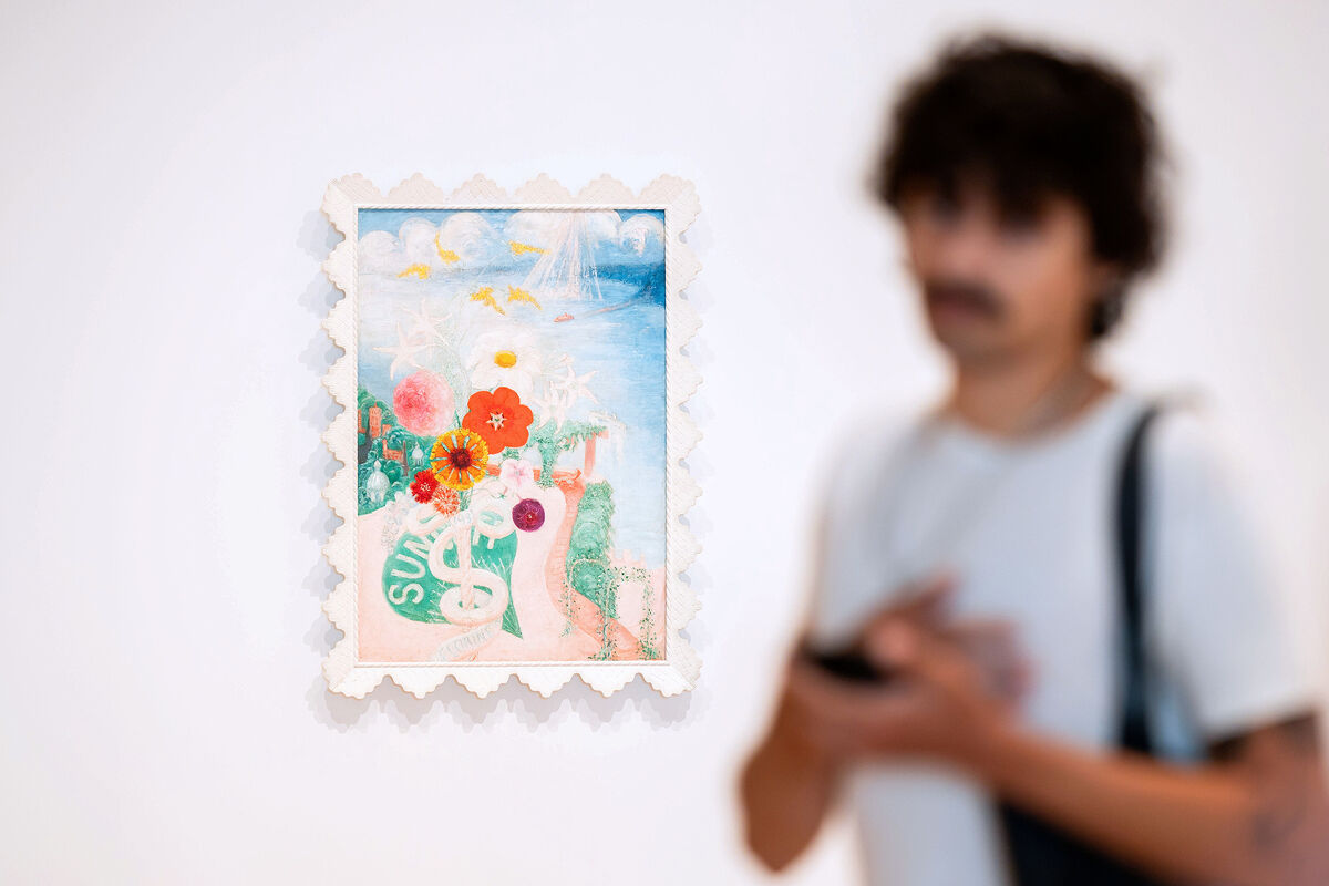 A colorful painting with flowers and the word "SUR" on display, while a person stands blurred in the foreground.