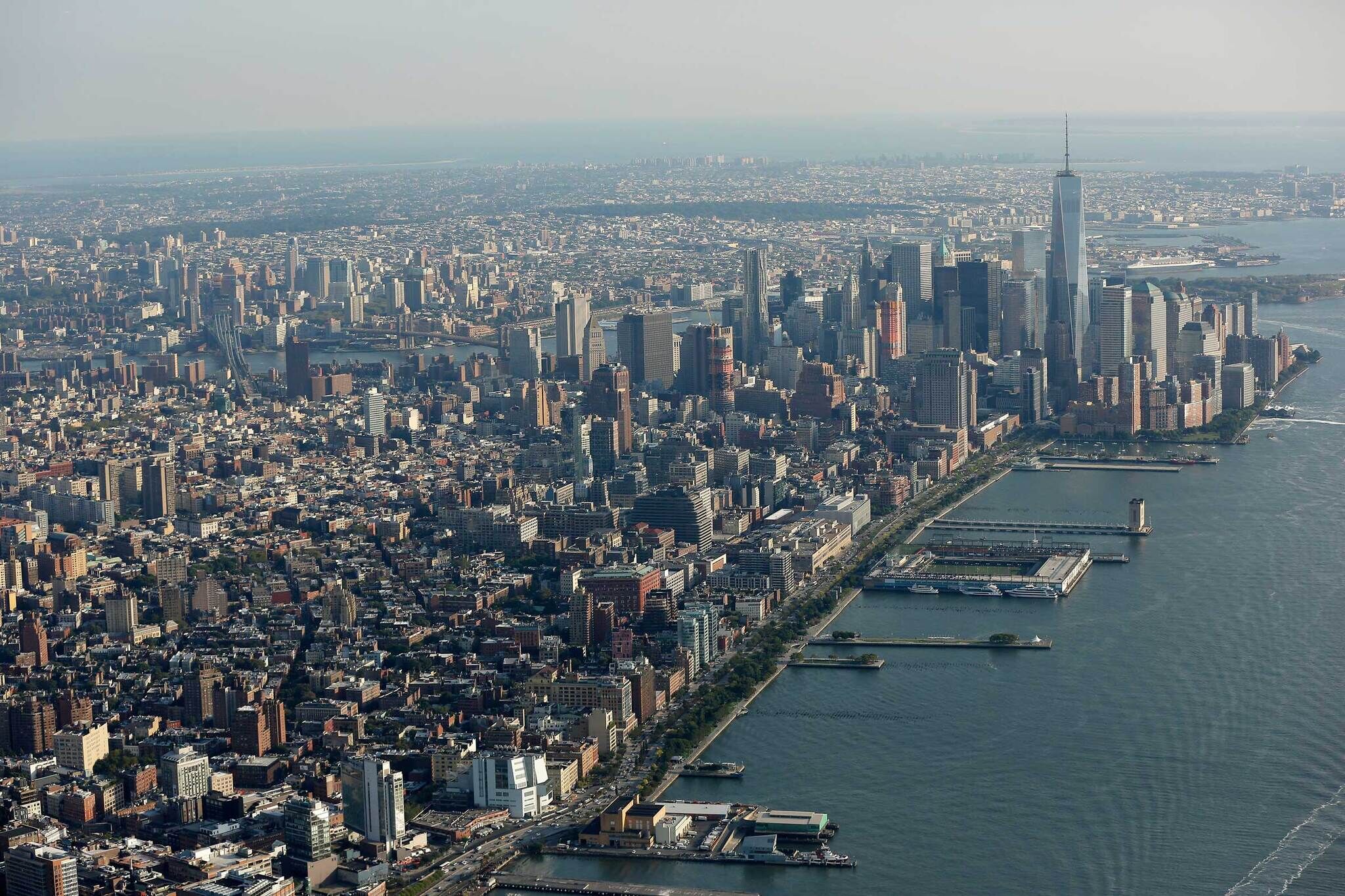 Aerial view of a large city skyline with tall buildings next to a river and several piers.