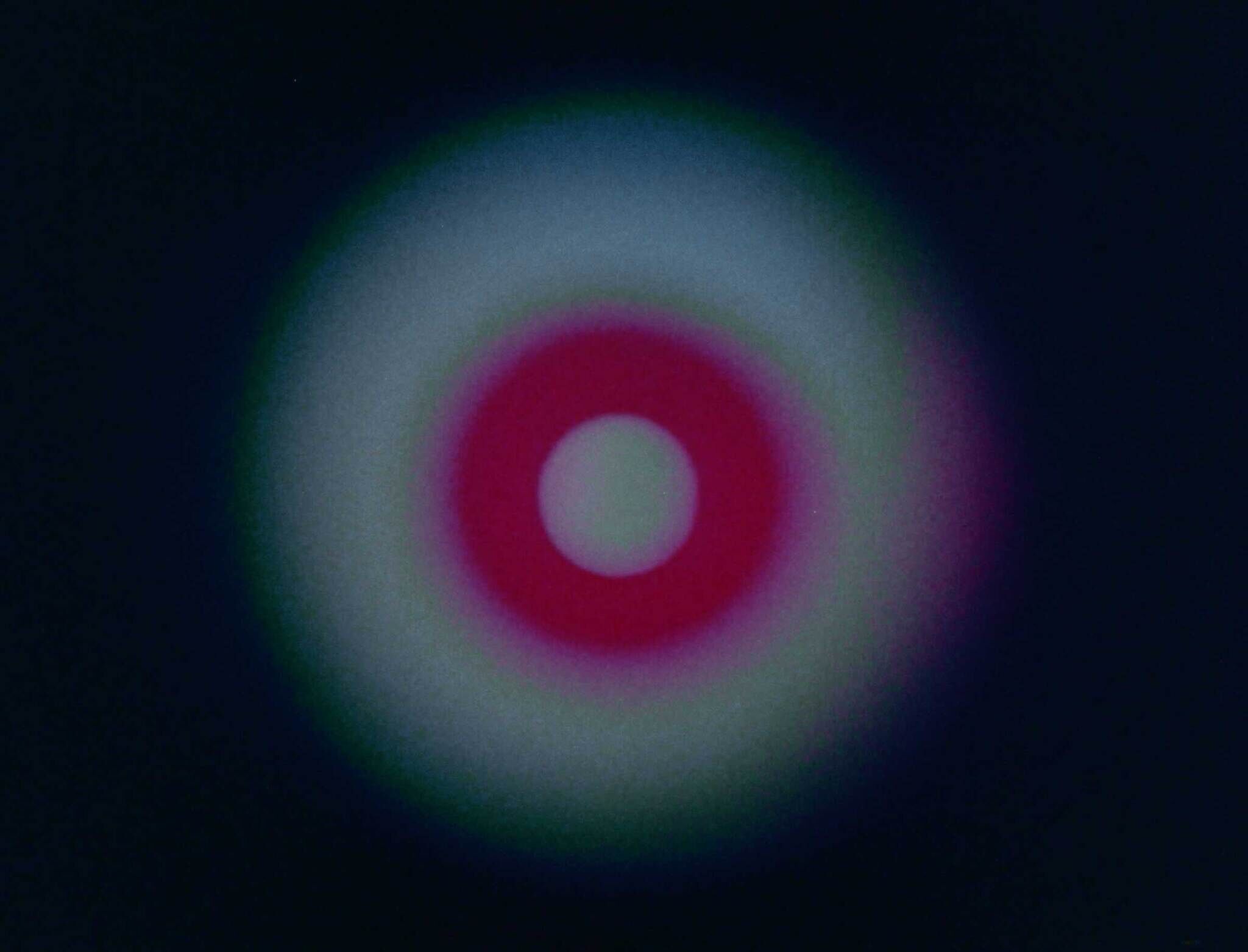 A glowing target shape with a red ring and white center on a dark background. No text present.