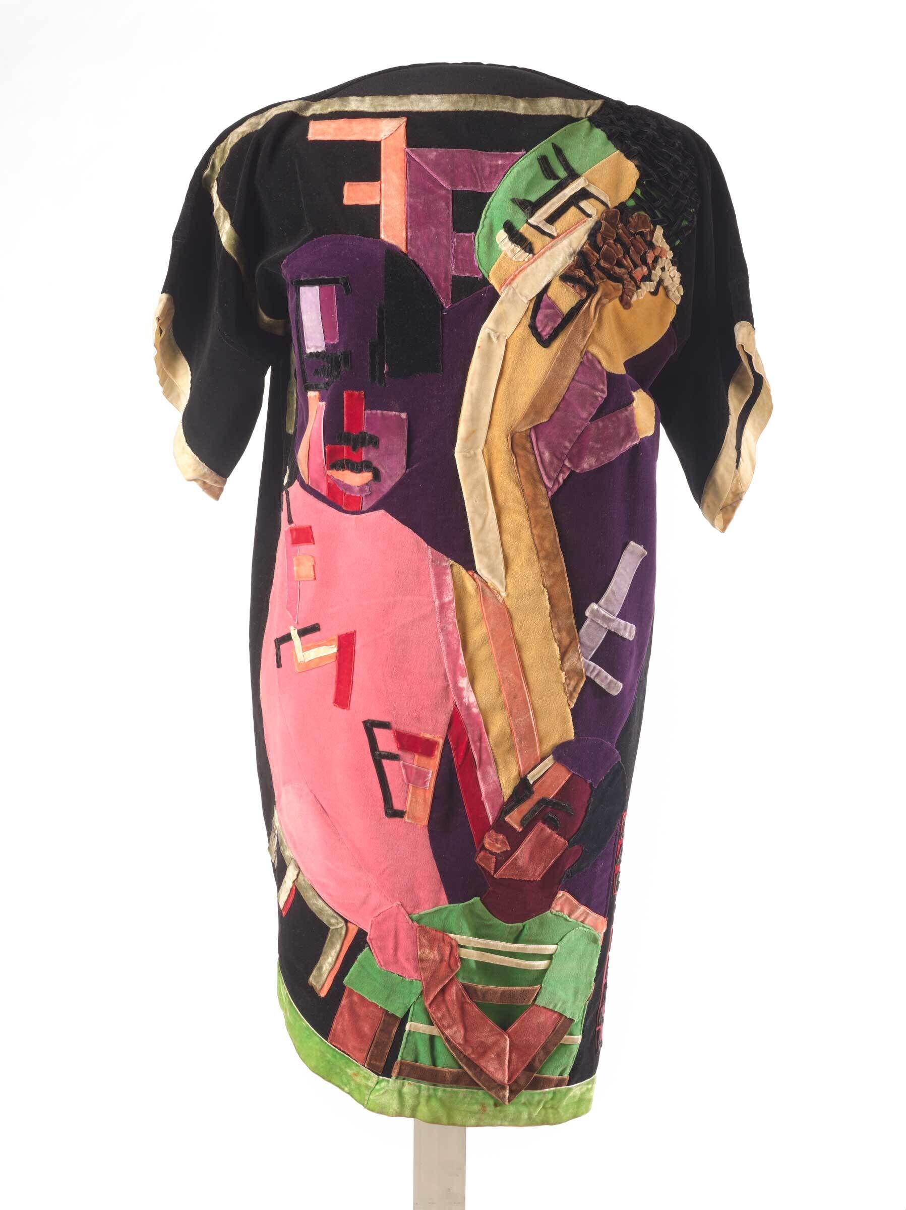 Colorful dress with abstract, geometric faces and shapes in pink, green, purple, and gold fabric patches.