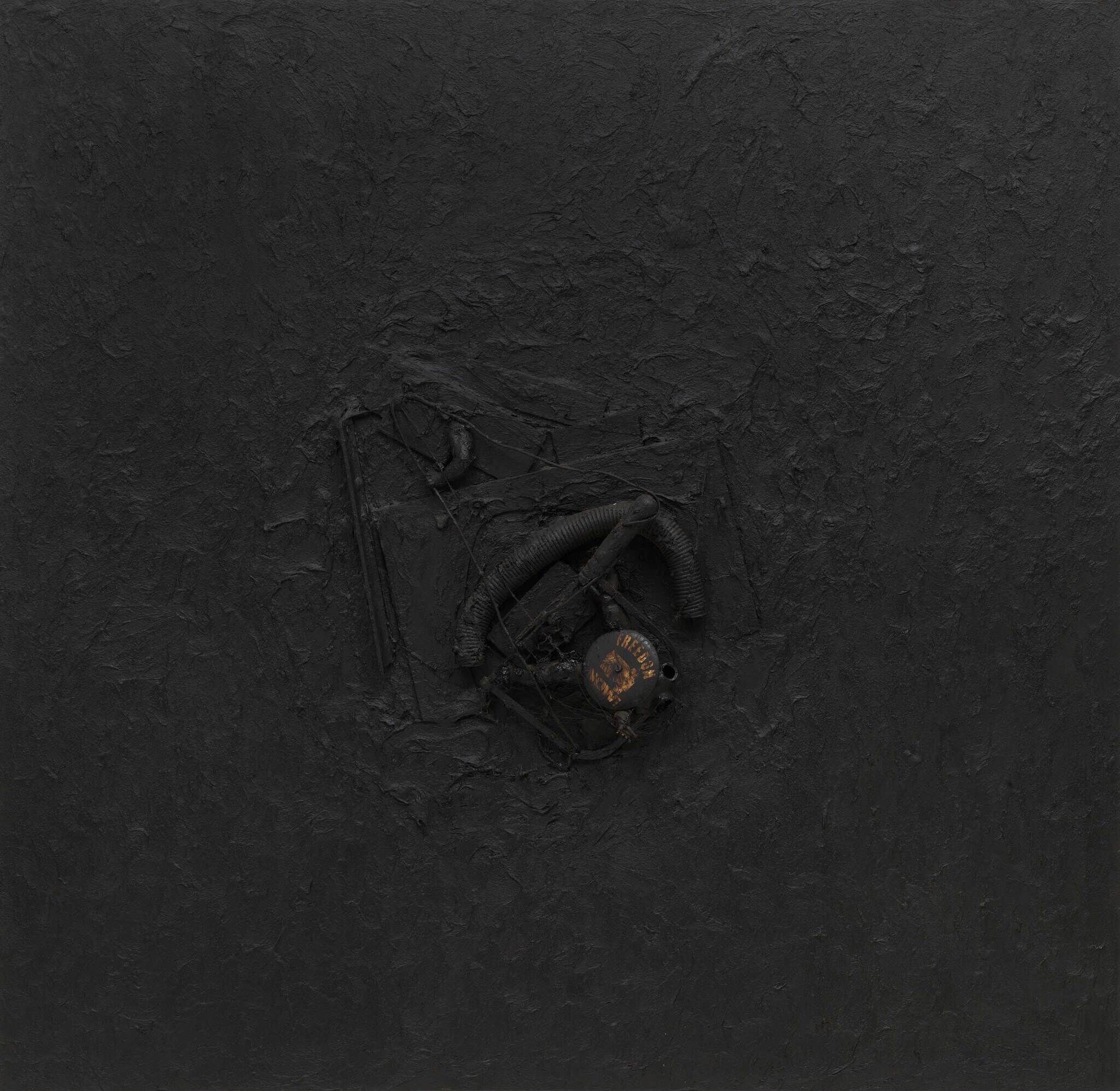 A dark, textured surface with a small, blackened gas mask in the center. The mask reads “INCOMBUSTIBLE.”