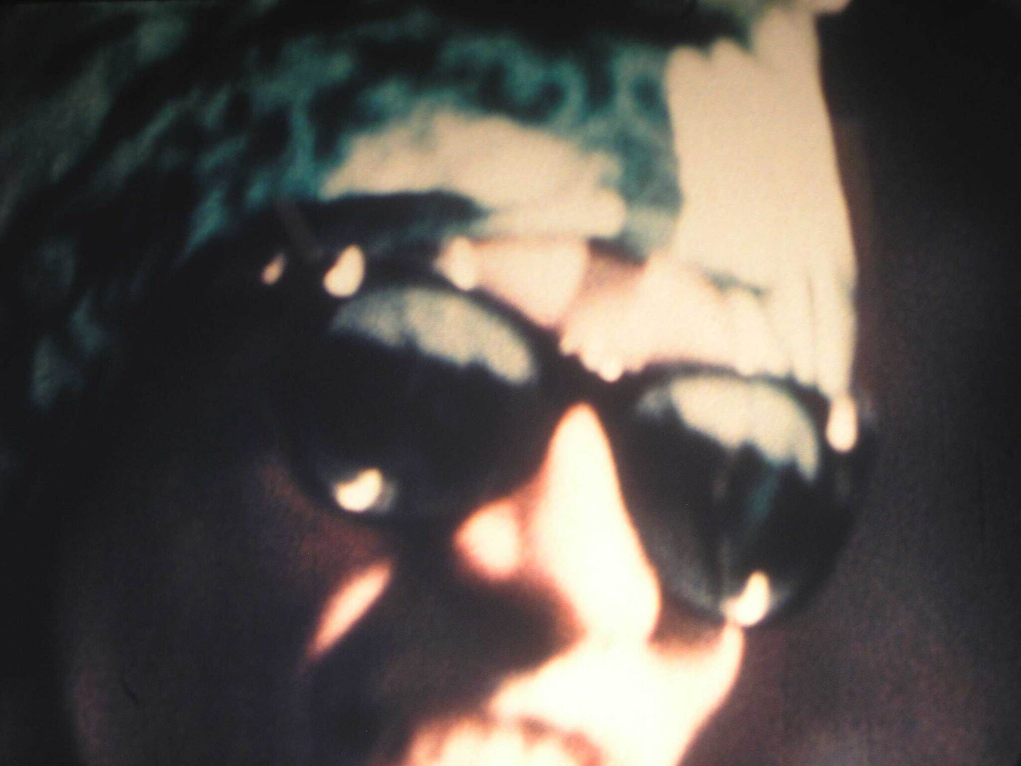 Person wearing dark sunglasses and a headscarf, with the image appearing blurry and out of focus.