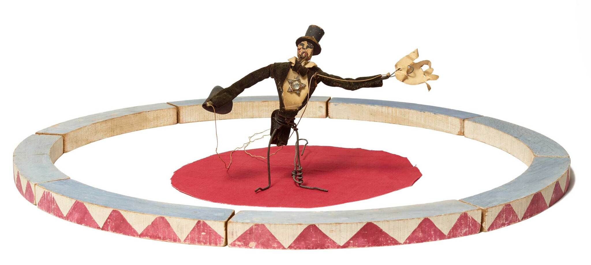 A circus ringmaster puppet with a top hat stands in the center of a small circular stage.