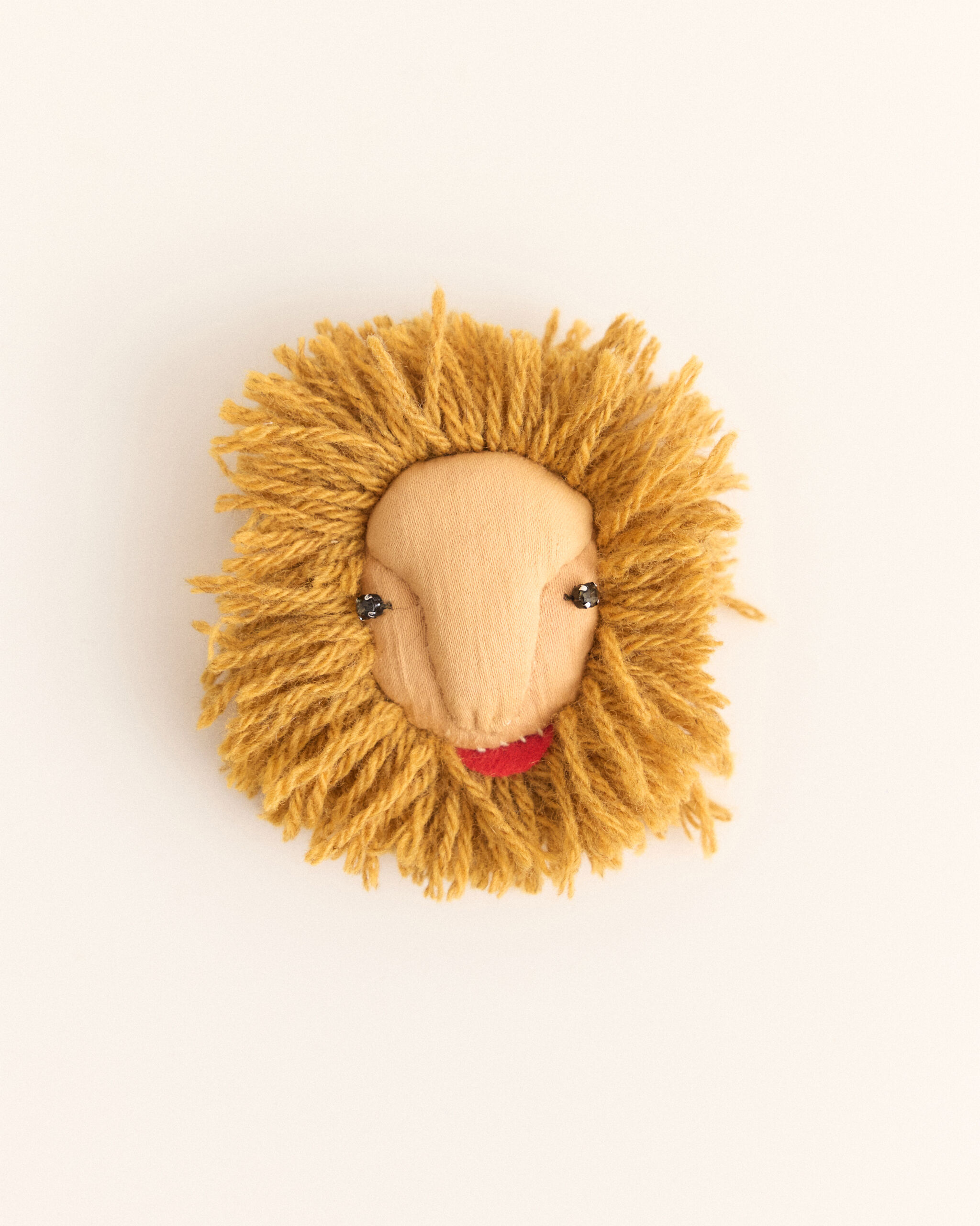 A small handmade lion face with a yarn mane, button eyes, and a red mouth.