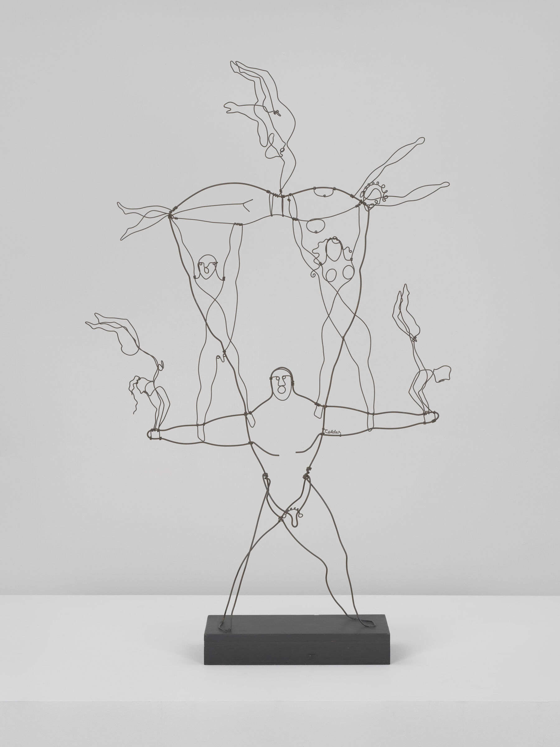 Wire sculpture of a strong man balancing three acrobats stacked above him.