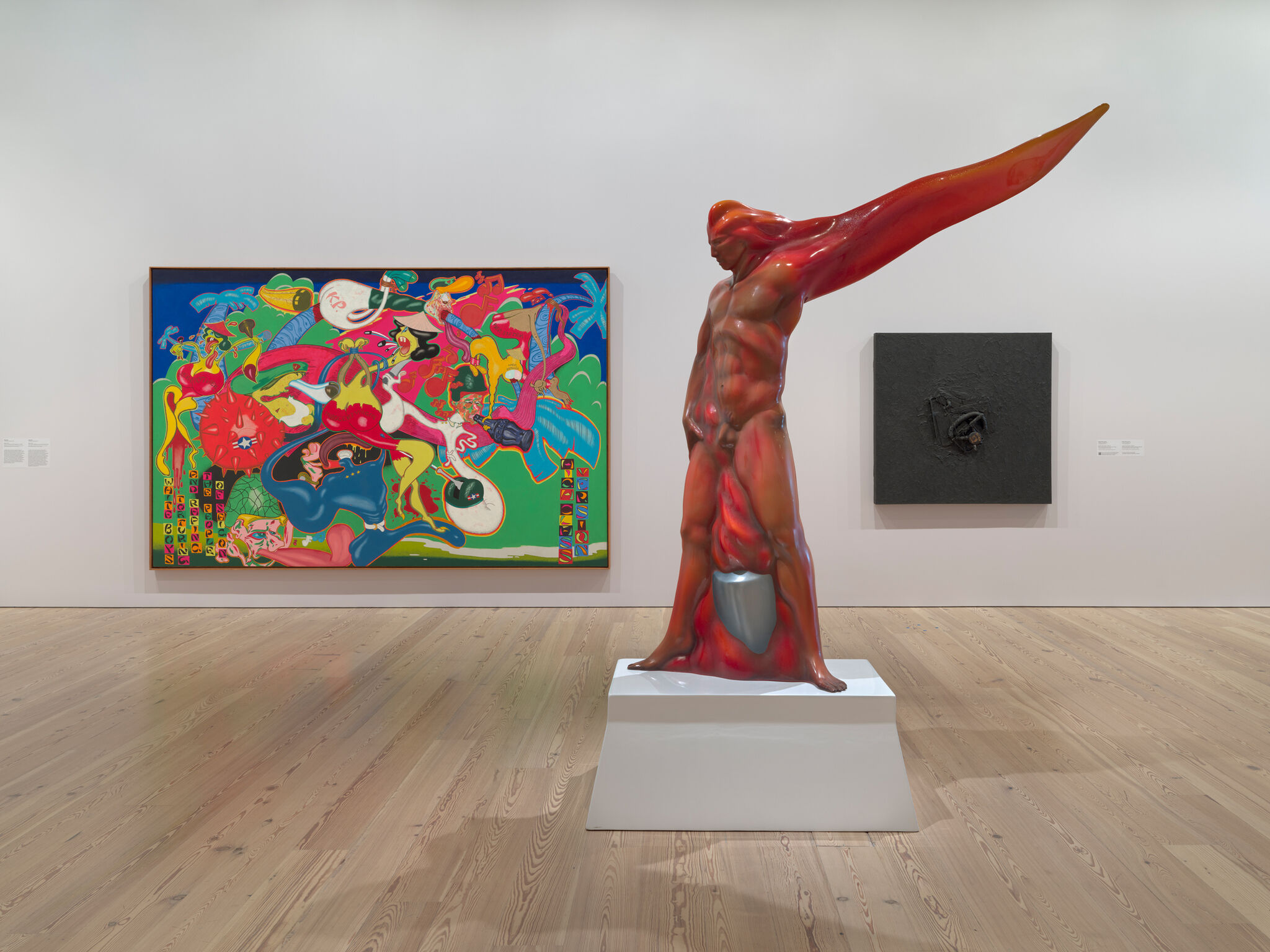 Red glossy humanoid sculpture with a long wing-like arm stands on a pedestal in a gallery.