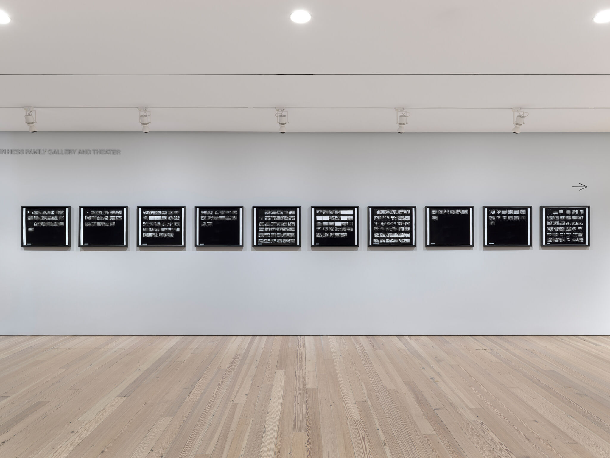 A gallery wall displaying eleven framed black-and-white contact-sheet photographs in a horizontal row.