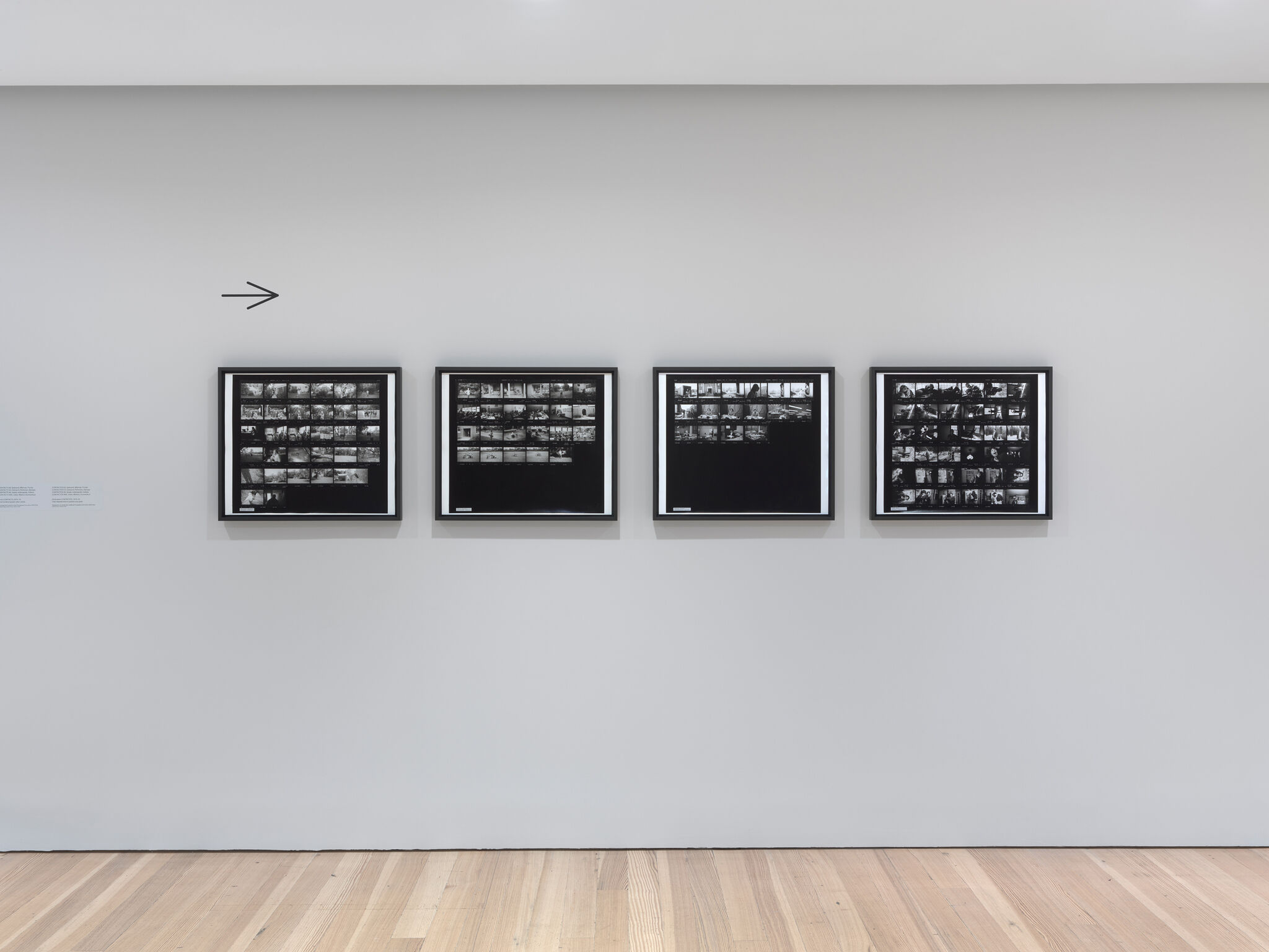 Four framed black-and-white contact sheet photographs hung evenly on a pale gray wall.