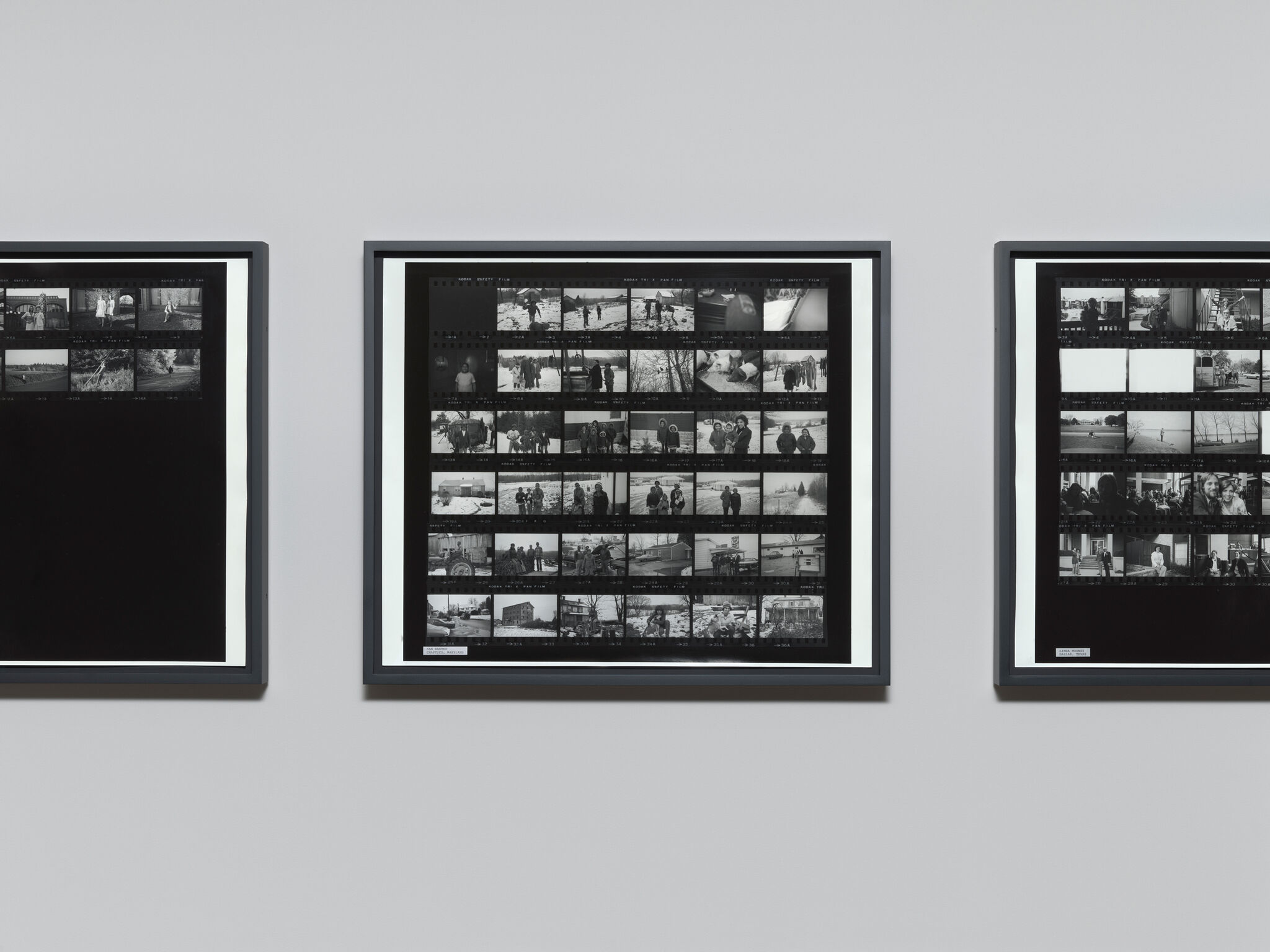 Three framed black-and-white contact sheets hang evenly spaced on a gray gallery wall.