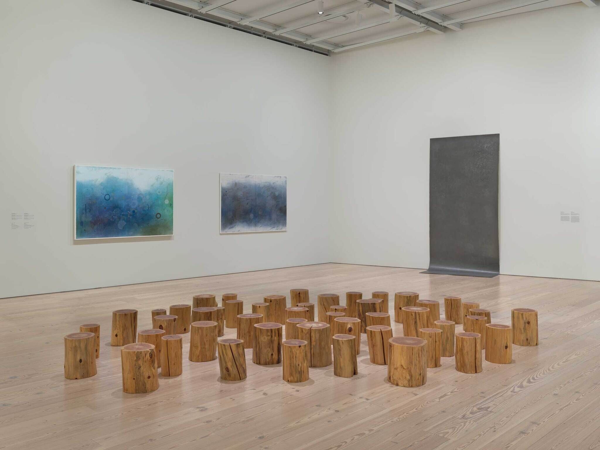 A gallery room with a cluster of short wooden log stools arranged on the floor.