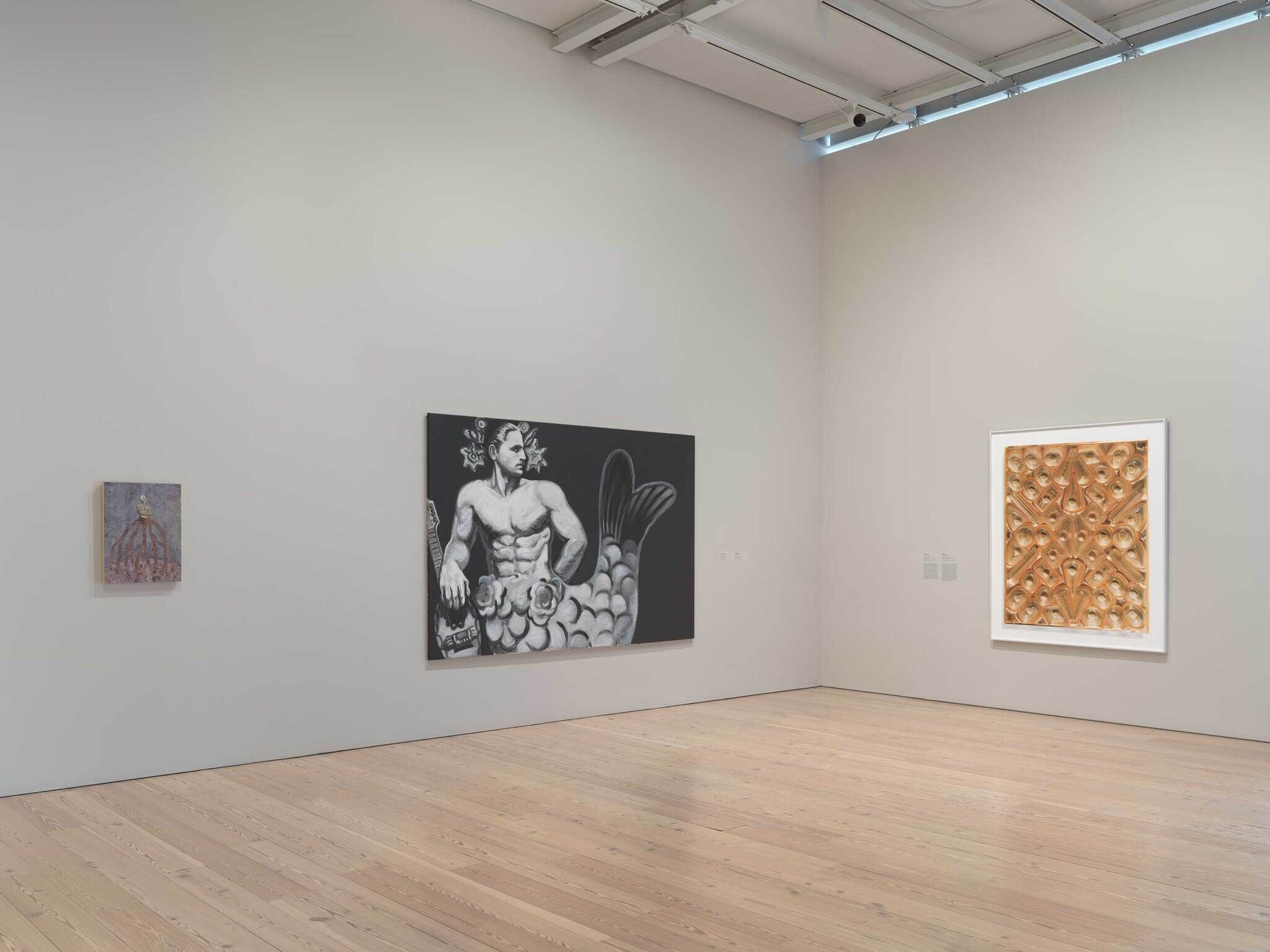 A gallery wall with three artworks including a large grayscale merman painting in the center.