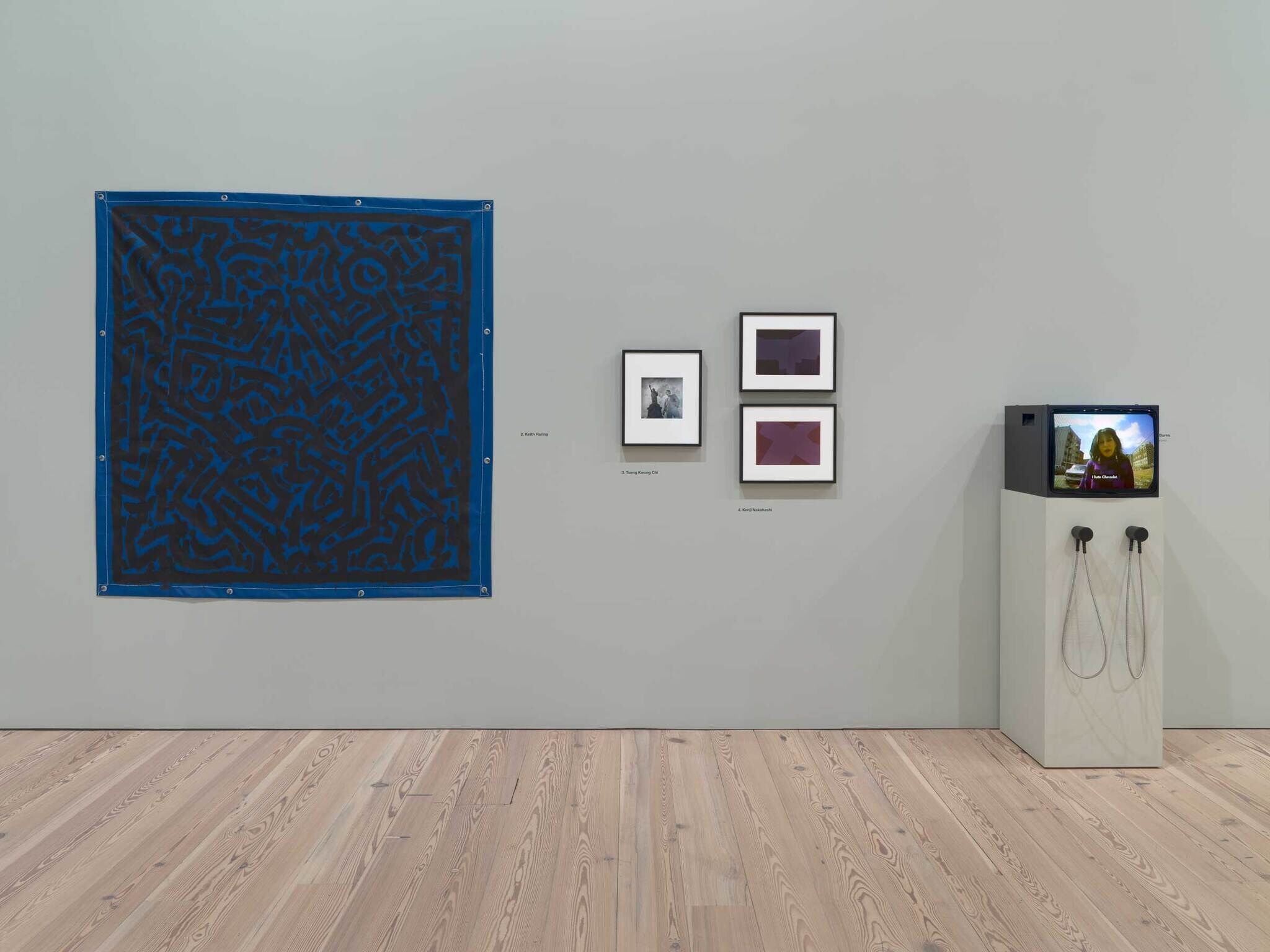 Large blue abstract textile, three framed artworks, and a vintage TV with headphones displayed on a pedestal.