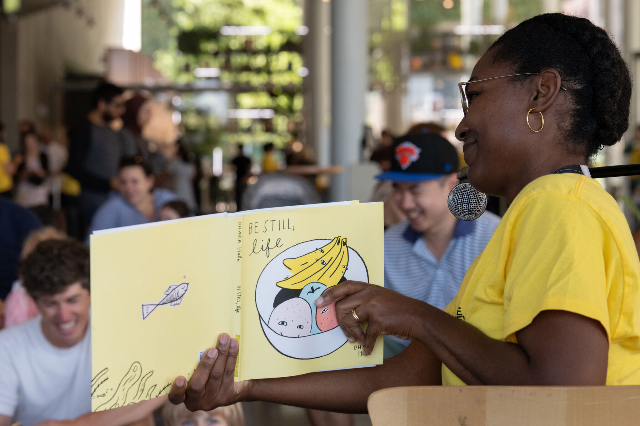 Dyeemah Simmons, Director of Learning and Social Impact at the Whitney, holds a book while reading aloud to our families.