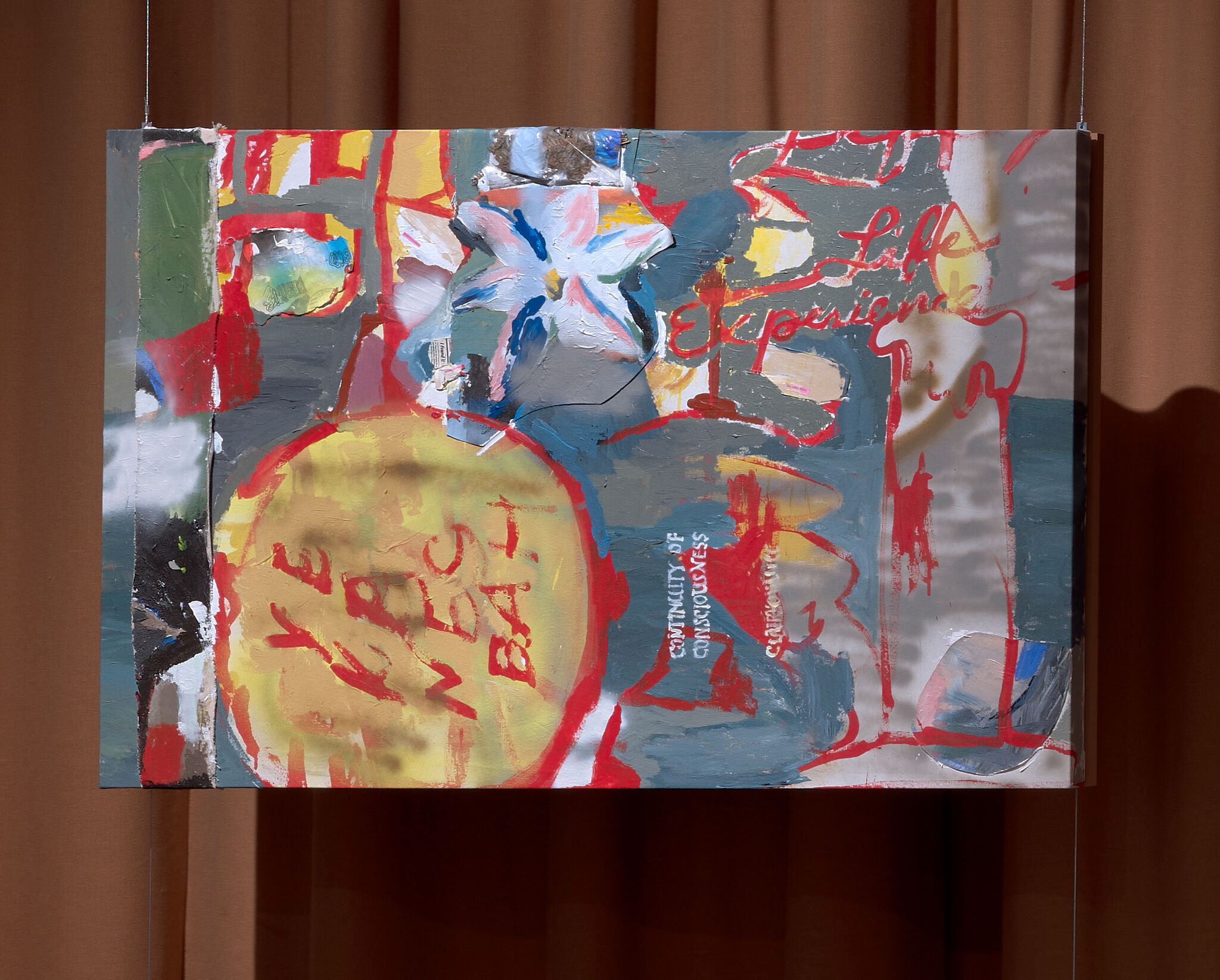 Abstract mixed-media painting with bright red and yellow shapes hung against brown curtains.