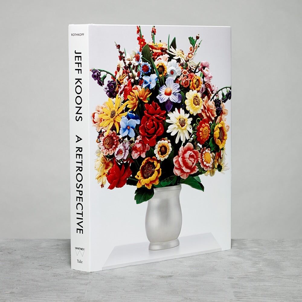 Hardcover book showing Jeff Koons retrospective with colorful flower sculpture on cover.