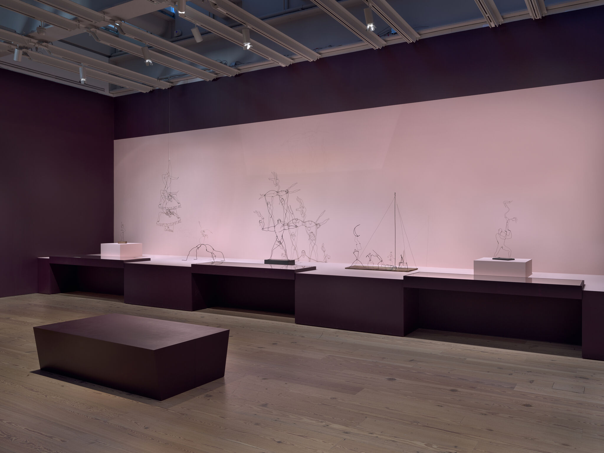 A dim gallery with wire sculptures.