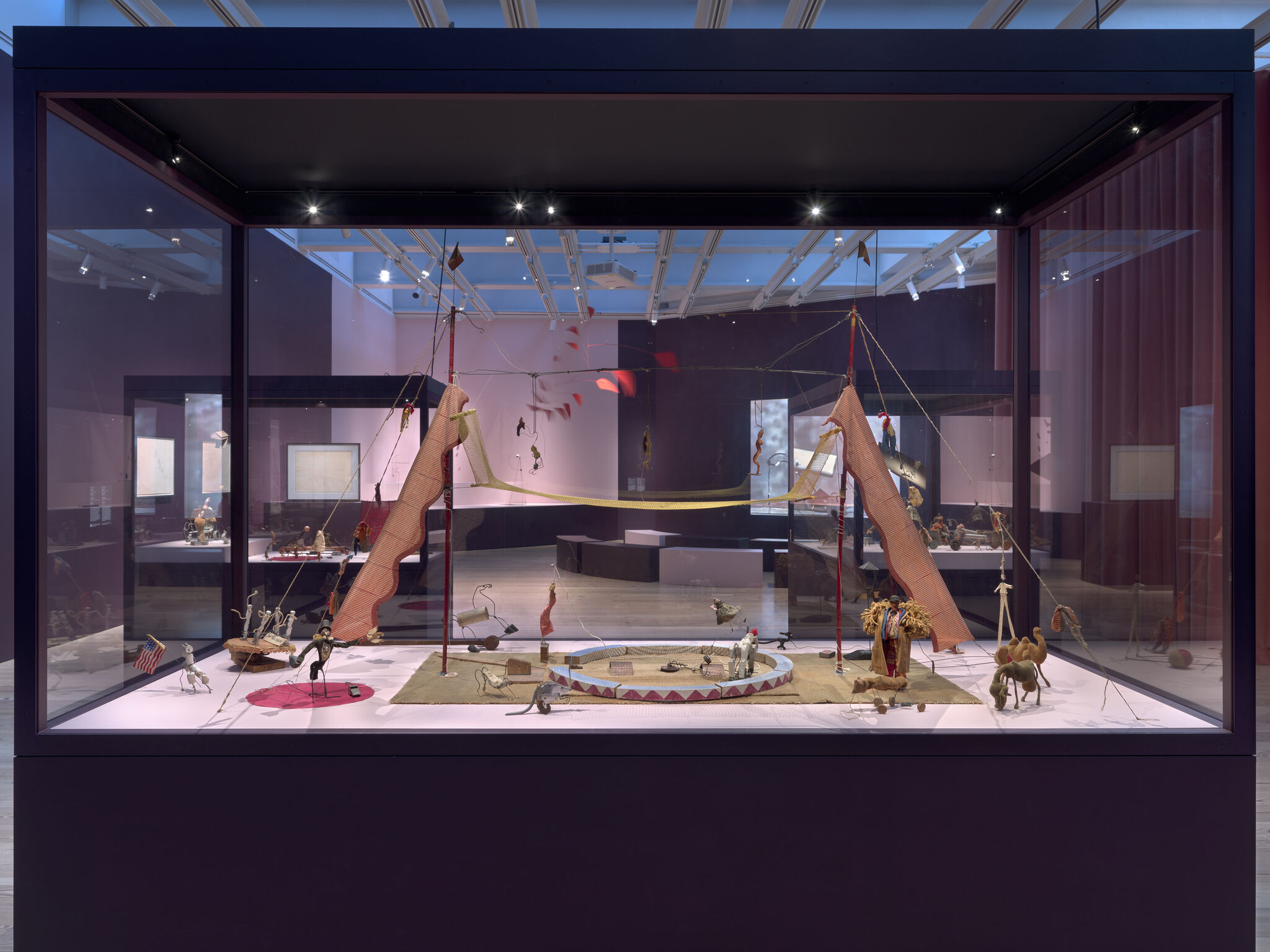 Miniature circus diorama with tent, performers, and animals displayed inside a glass vitrine.