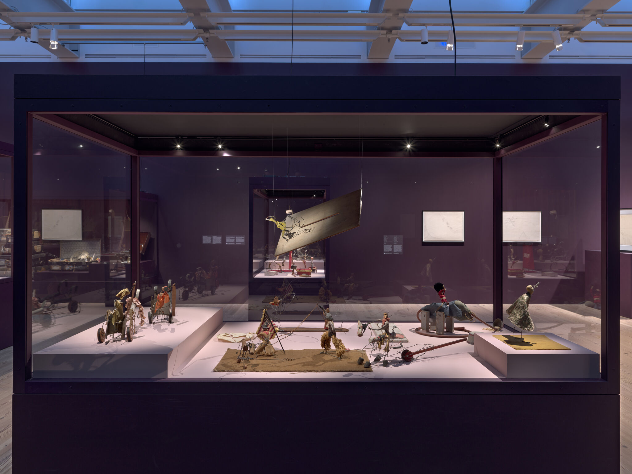 A museum display case with small mechanical puppets and miniature contraptions arranged on platforms.