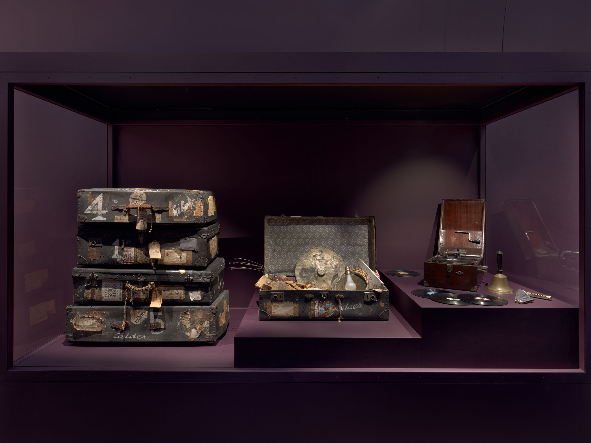 A display of worn travel trunks and an open case with musical items and a gramophone.