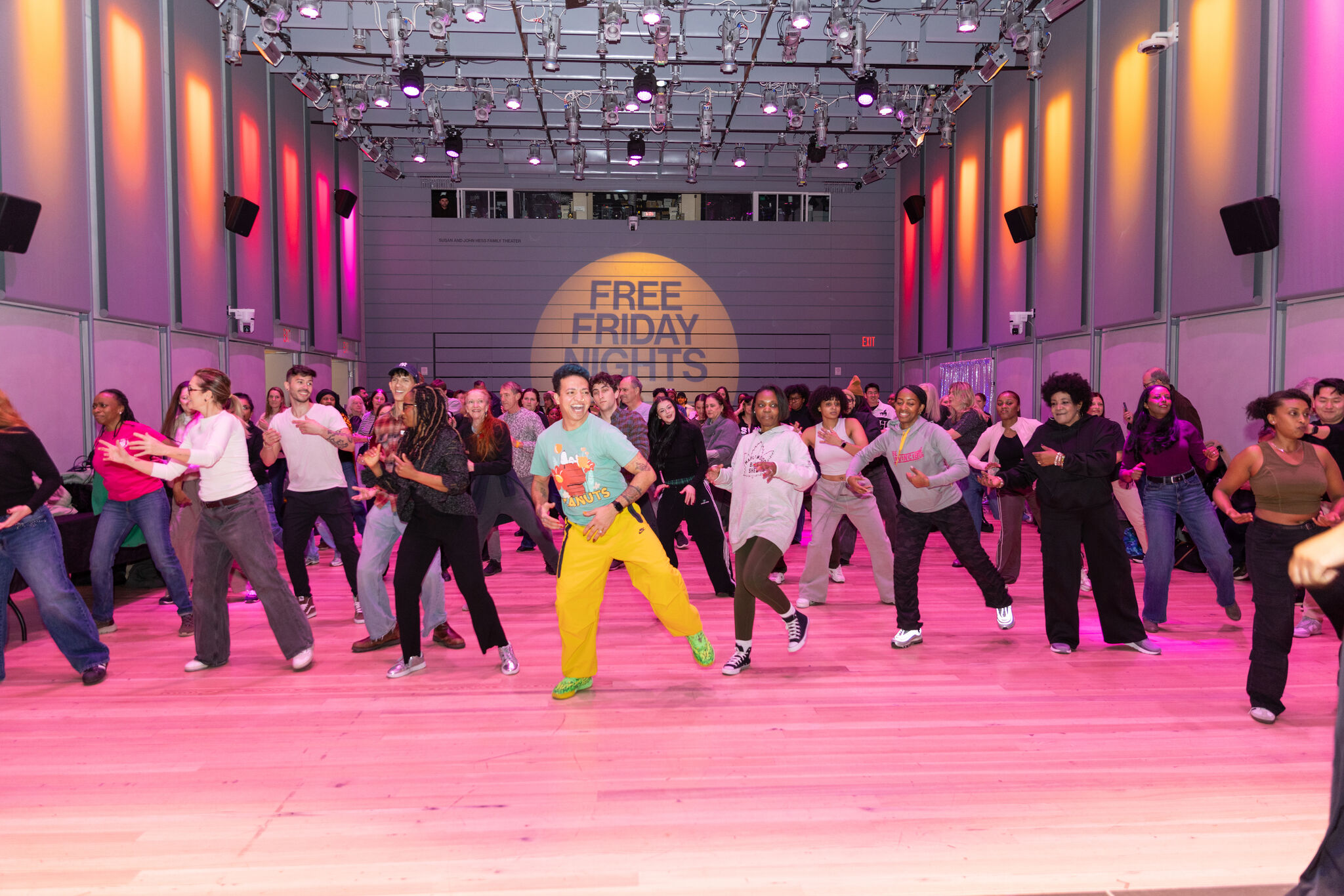 A lively dance instructor leads a large crowd of people during Free Friday Nights event.