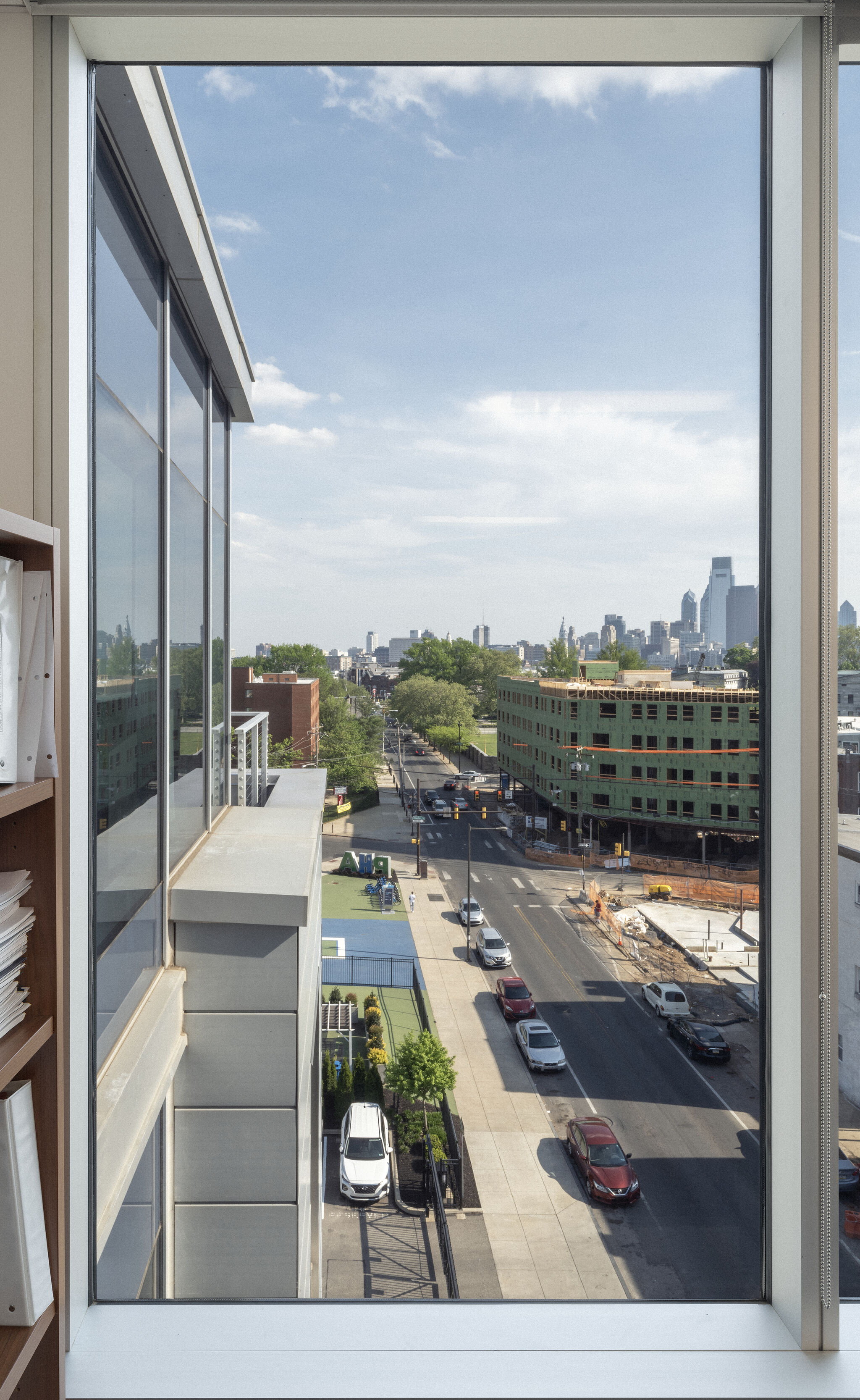 A city street with cars and building construction seen through a tall office window.