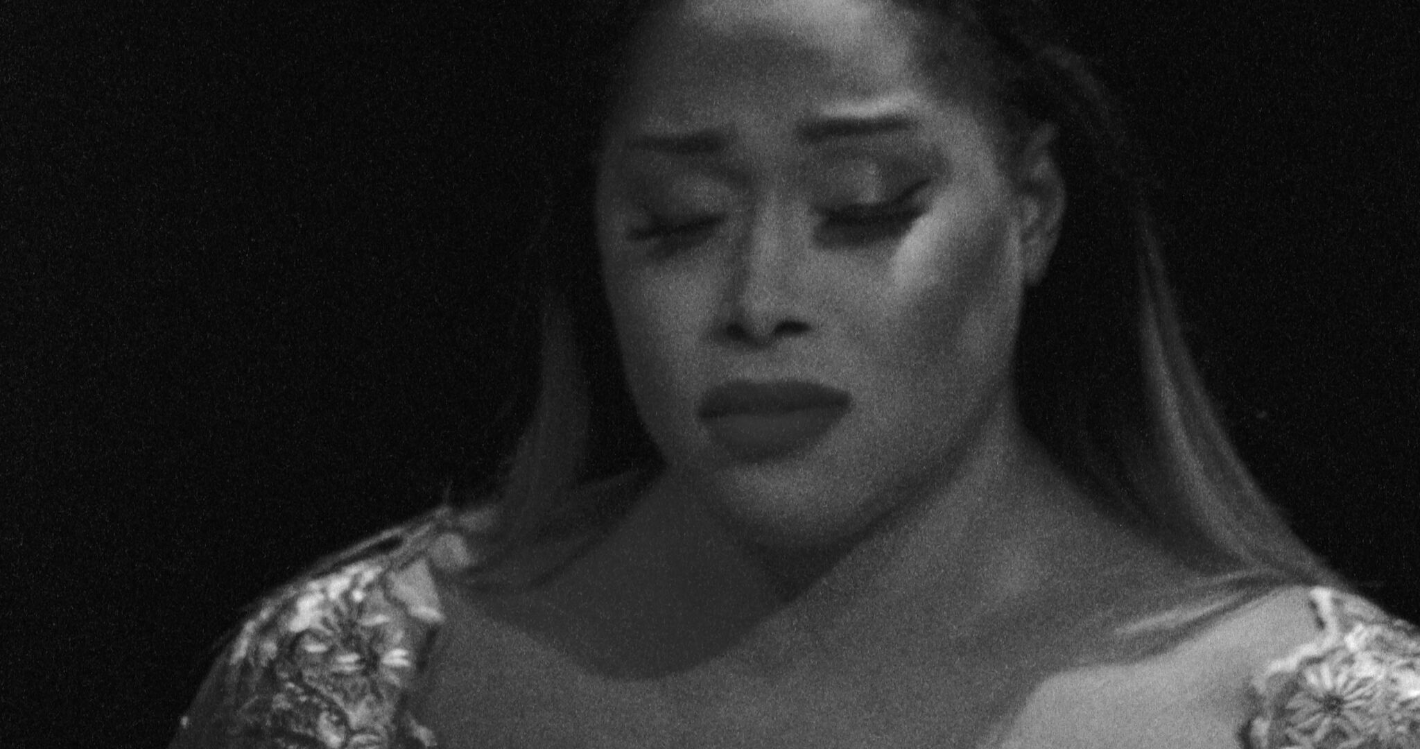 A woman with closed eyes and downturned mouth looking sad and reflective.