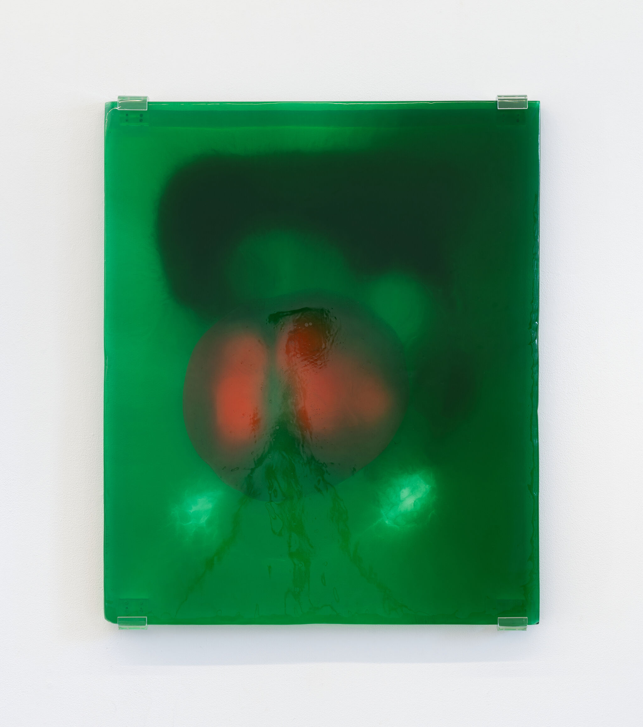 A translucent green resin panel mounted on a white wall with two glowing red circular forms inside.