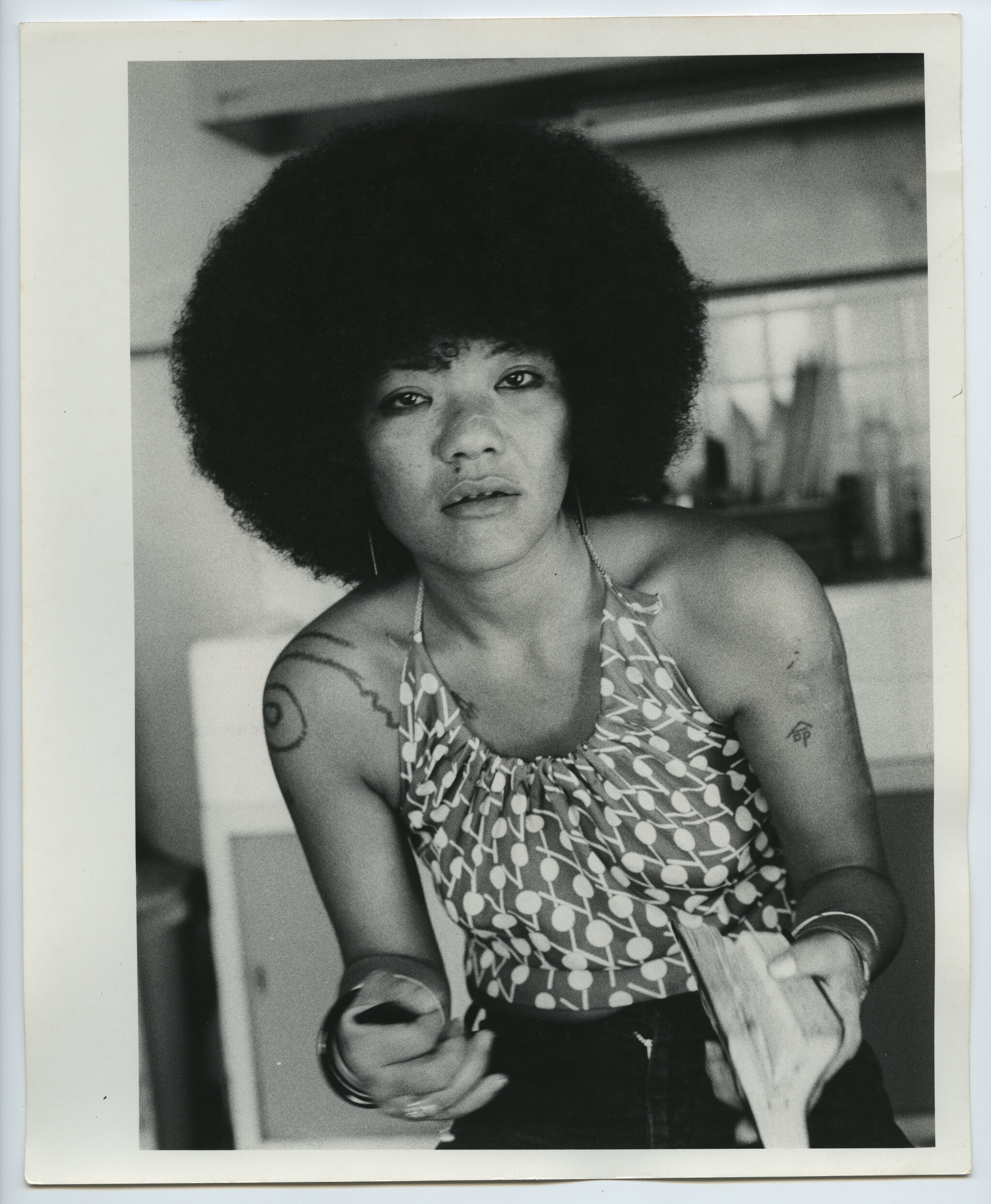 Young woman with an afro looks at the camera while offering a stack of bills.