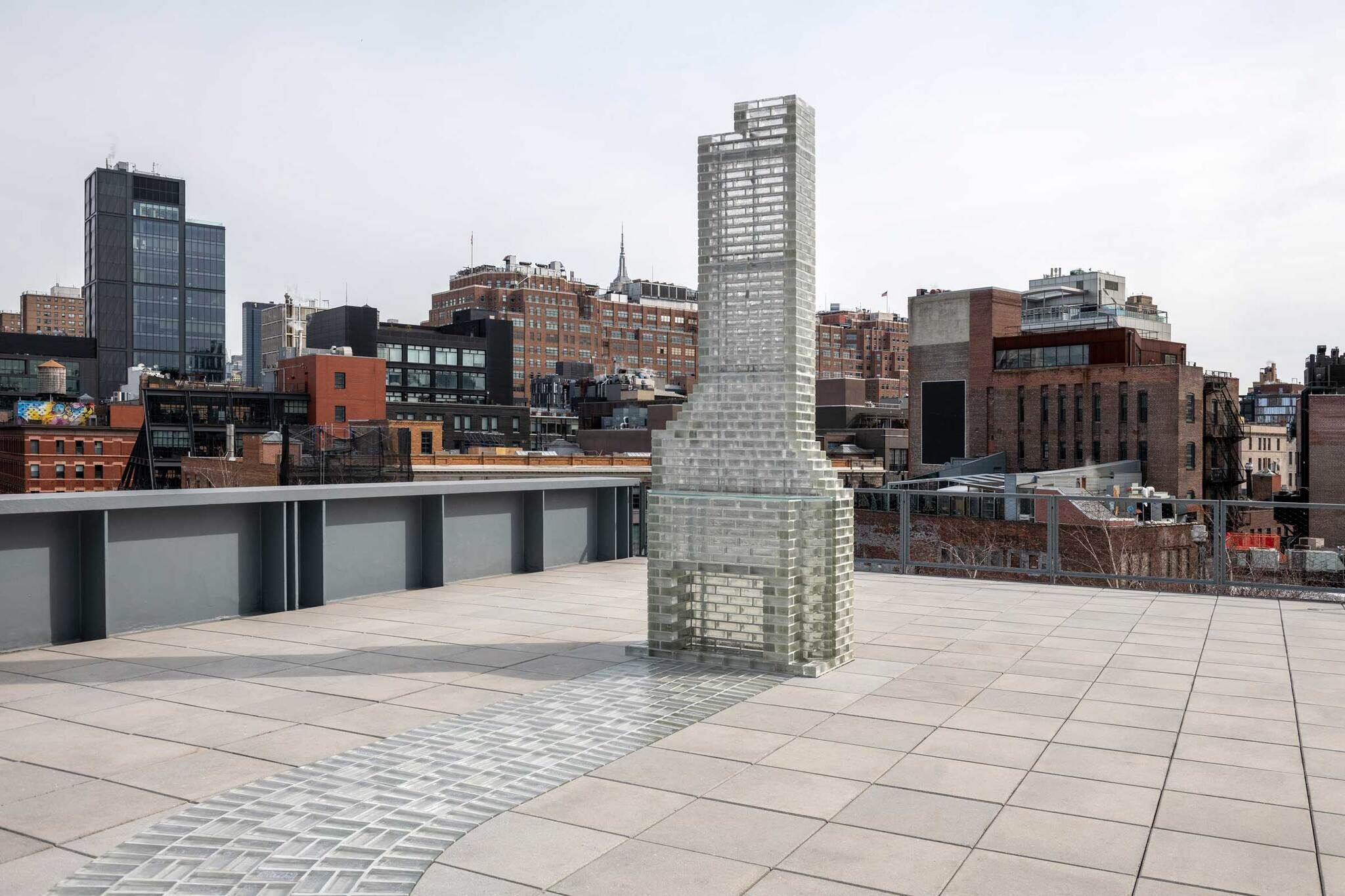 A tall glass-brick sculpture with a matching glass path sits on a rooftop.