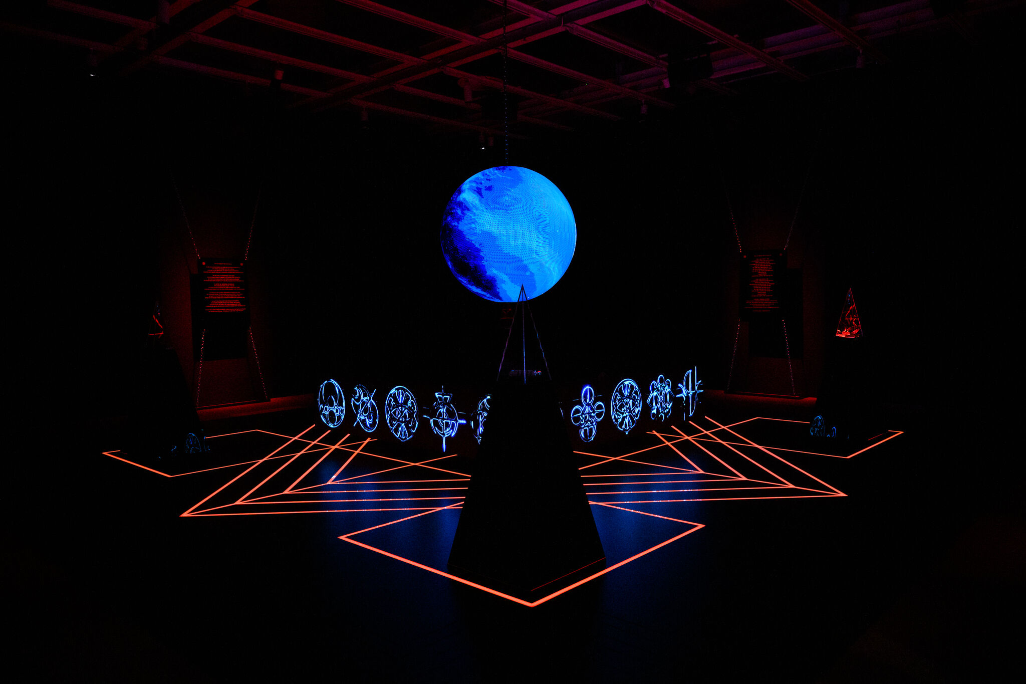 A glowing blue globe hangs above a dark pedestal surrounded by neon orange floor lines.