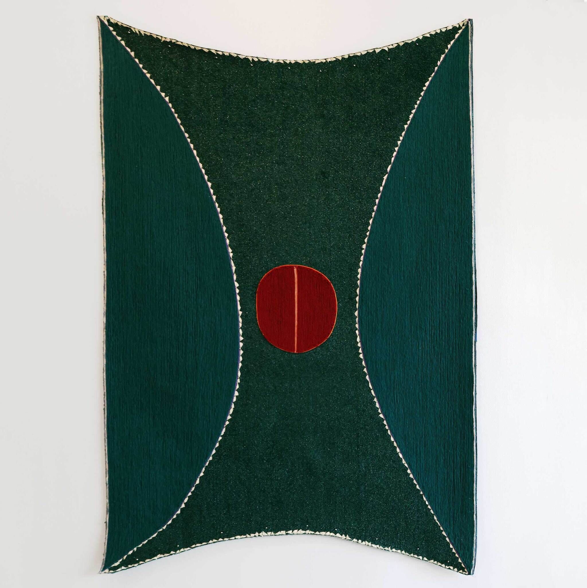 A large green textile wall hanging with curved teal panels and a central red circular patch.